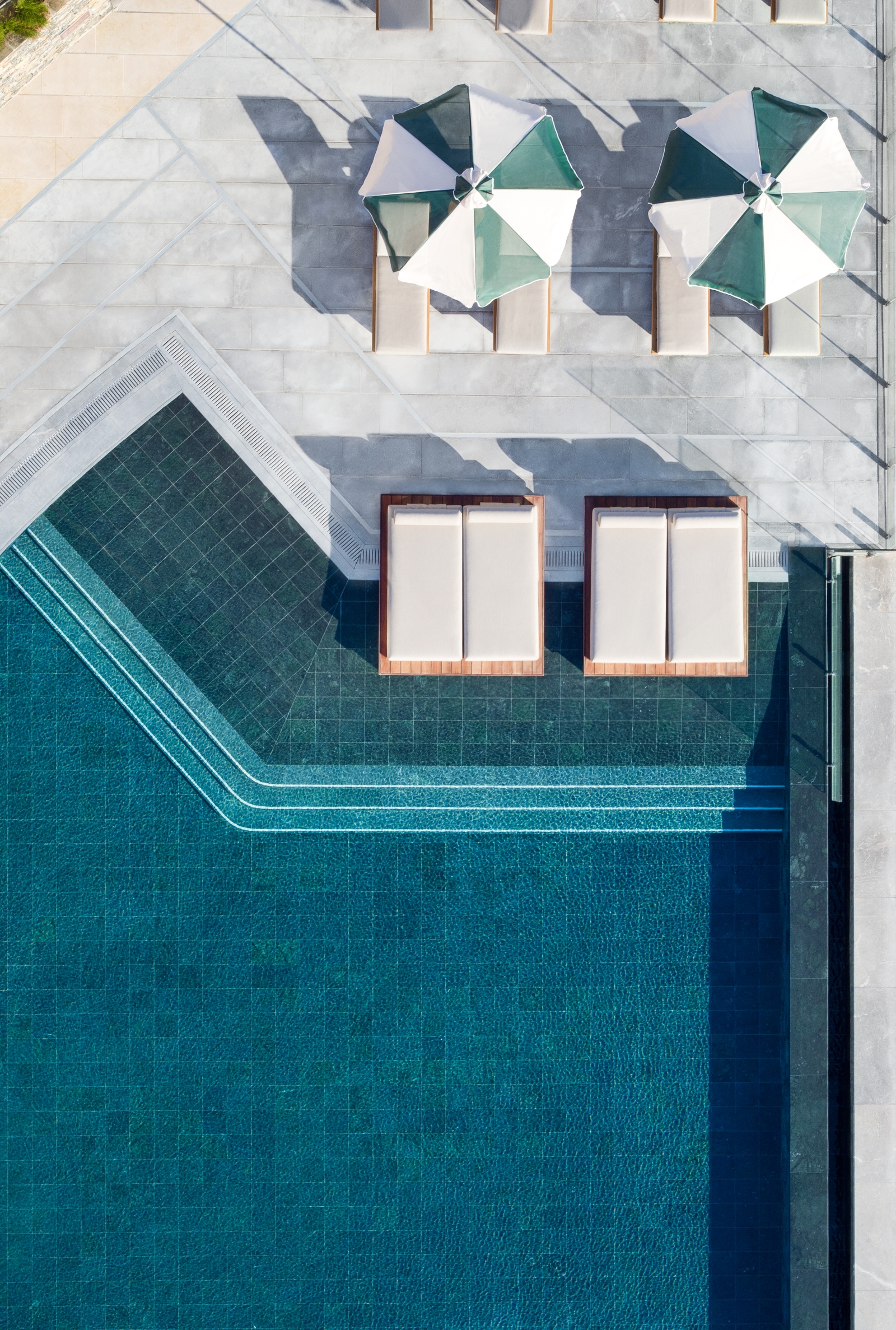 Aerial view of the main pool with sun loungers and parasols at luxury resort Daios Cove in Greece