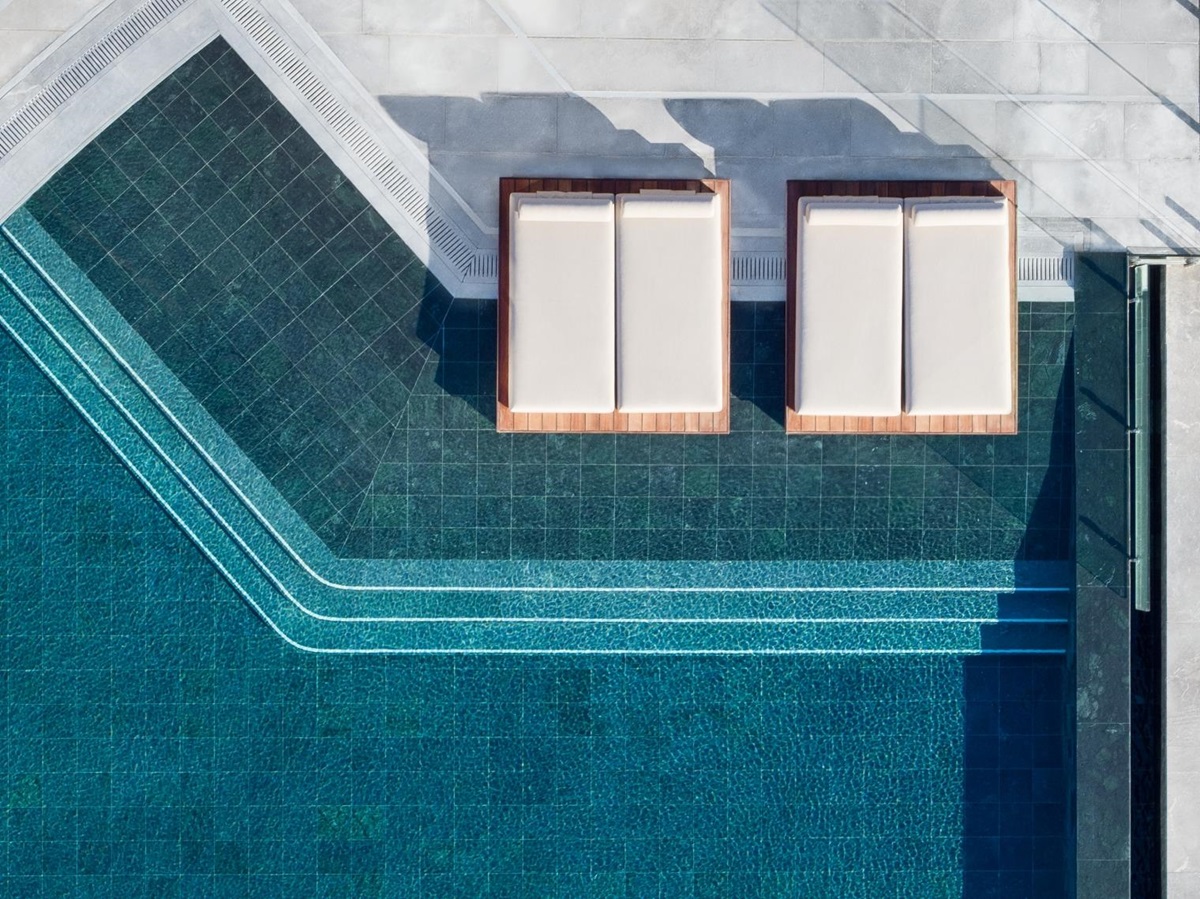 Aerial view of the main pool with sun loungers and parasols at luxury resort Daios Cove in Greece