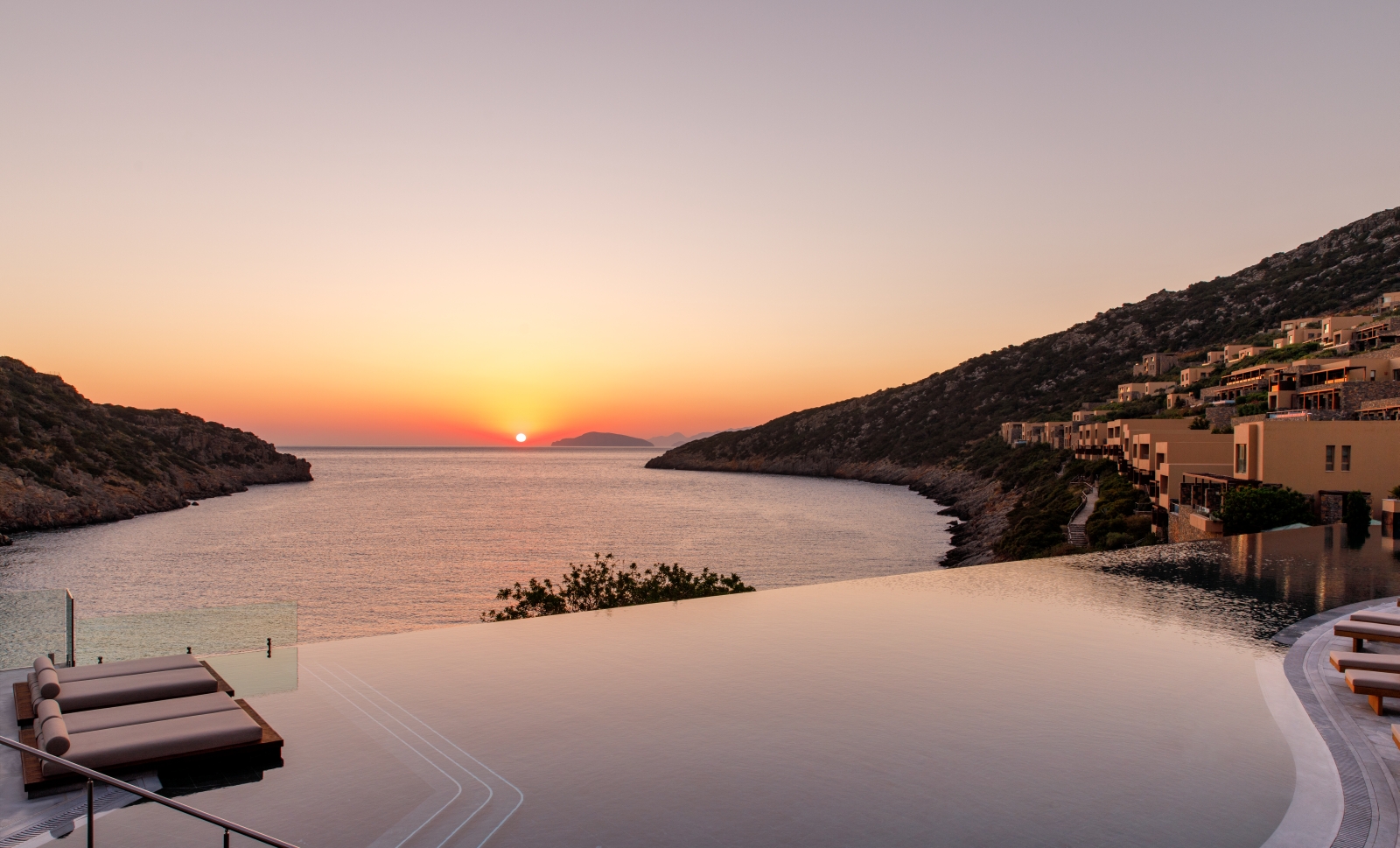 Sunrise over the main infinity pool and bay at luxury resort Daios Cove in Greece