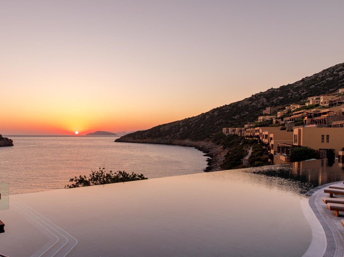 Sunrise over the main infinity pool and bay at luxury resort Daios Cove in Greece