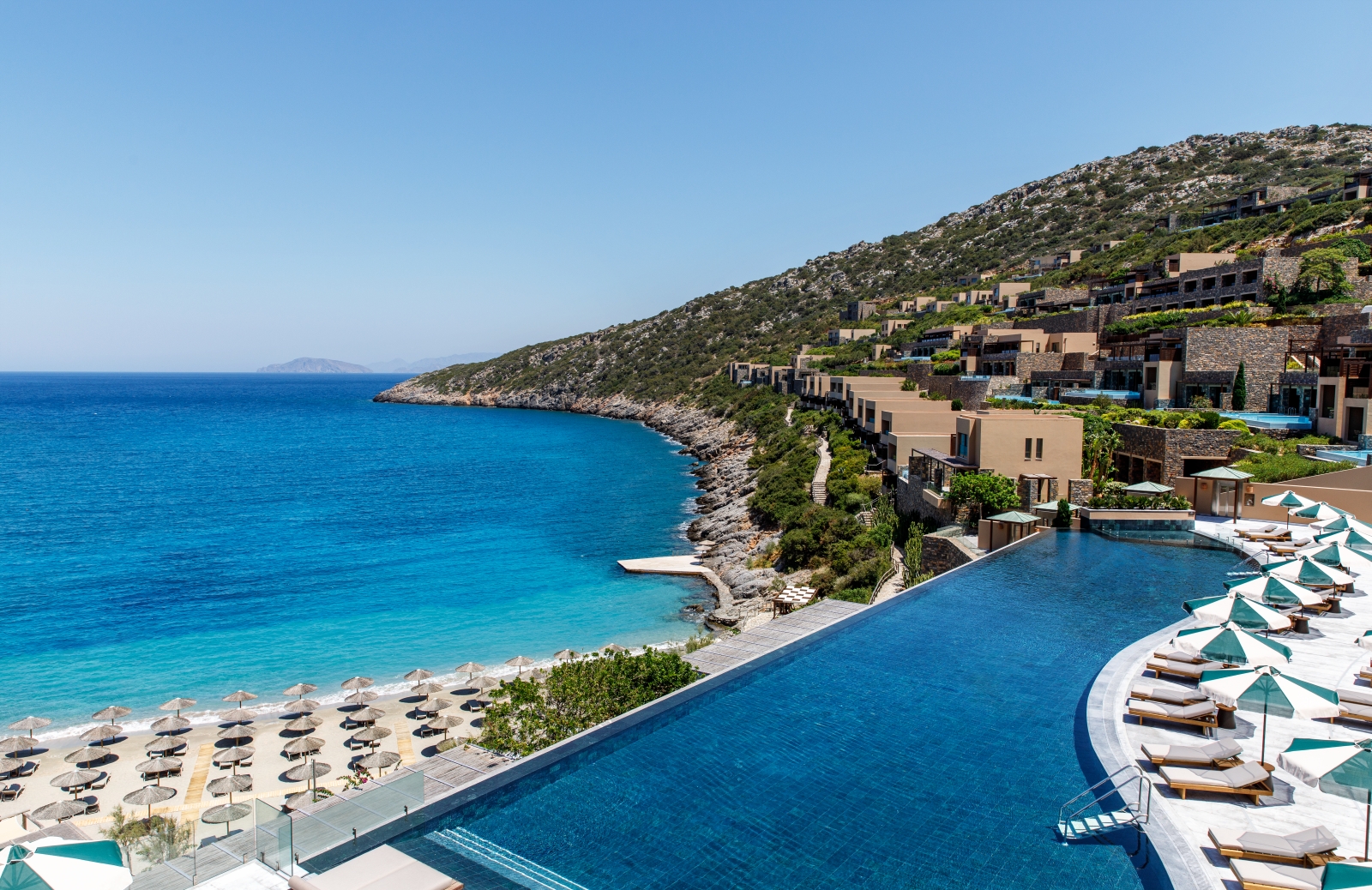 View over the main infinity pool, the beach and the bay at luxury resort Daios Cove in Greece