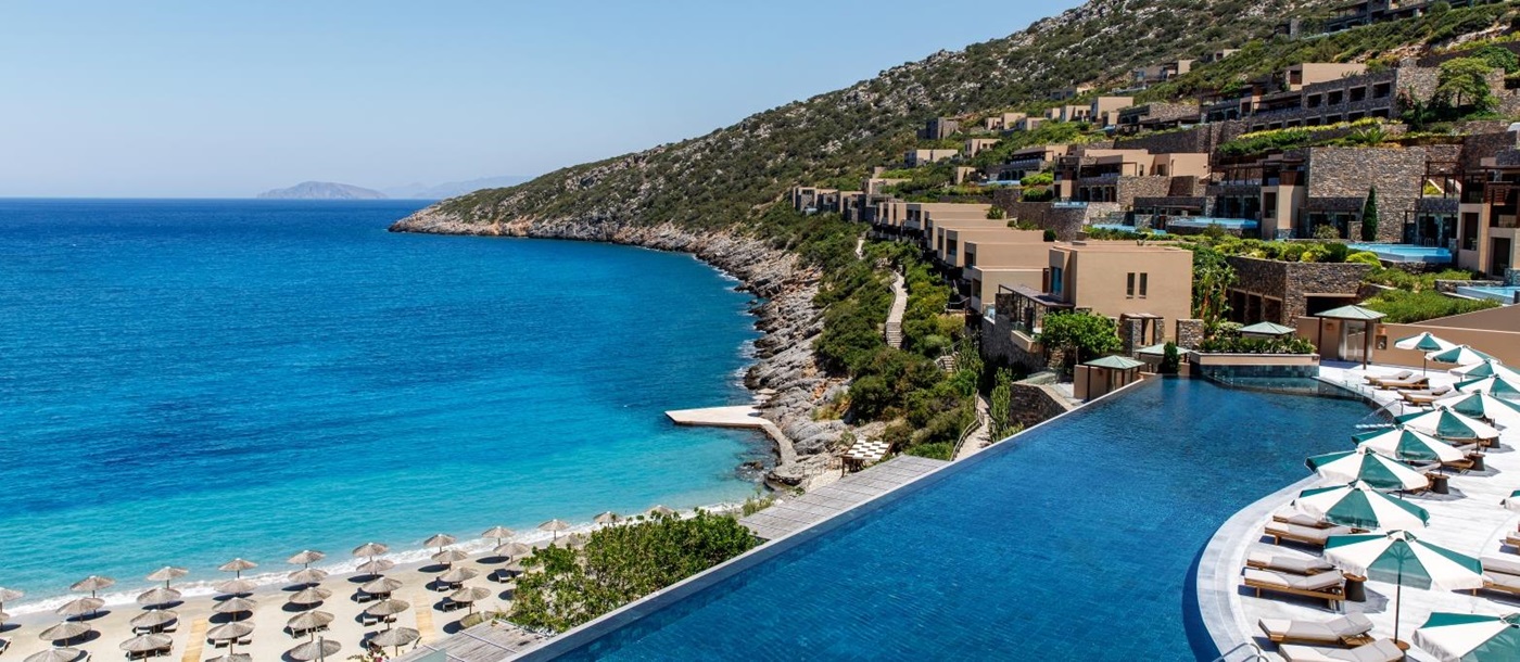View over the main infinity pool, the beach and the bay at luxury resort Daios Cove in Greece