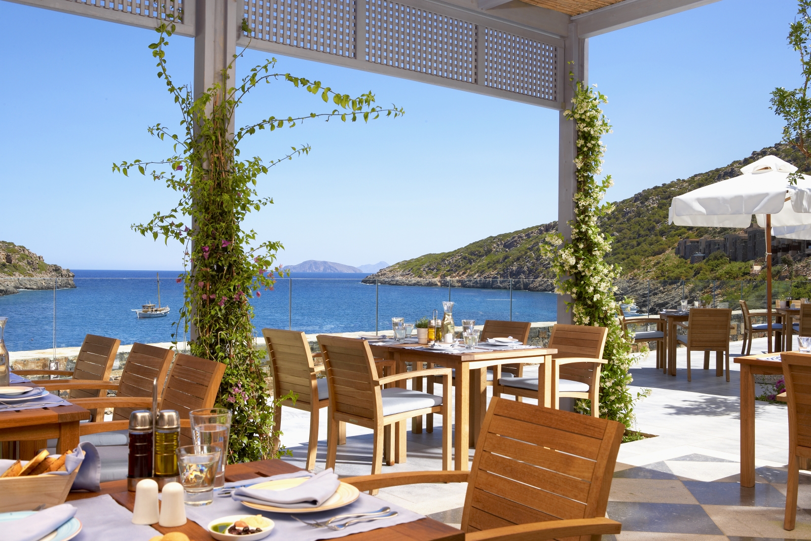 Mediterranean terrace dining at Taverna Restaurant overlooking the bay at luxury resort Daios Cove in Greece