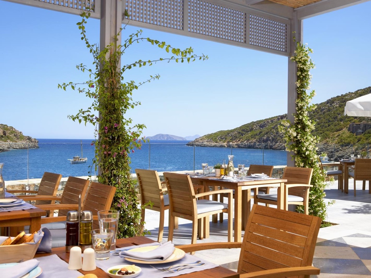 Mediterranean terrace dining at Taverna Restaurant overlooking the bay at luxury resort Daios Cove in Greece