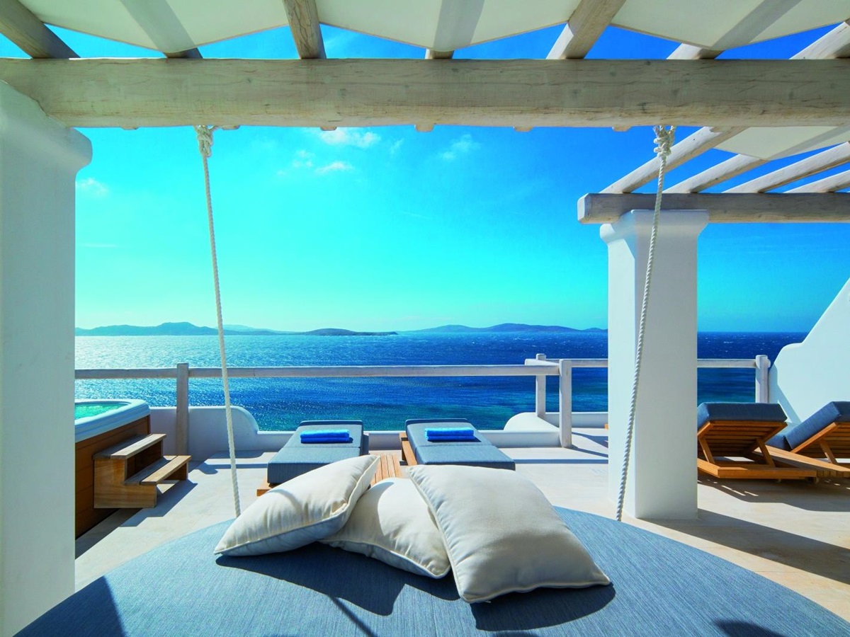 Terrace of an Executive Suite at luxury resort Mykonos Grand, Greece with sun loungers, jacuzzi and stunning views over the Aegean Sea