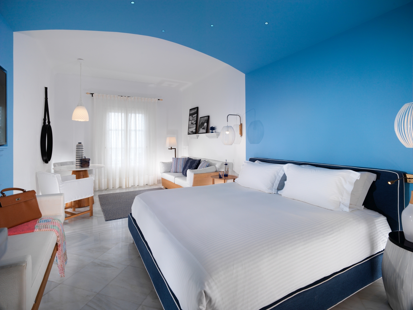 Interior of a Premium Sea View Room with double bed, flat screen TV and sitting area in maritime colours at luxury resort Mykonos Grand, Greece