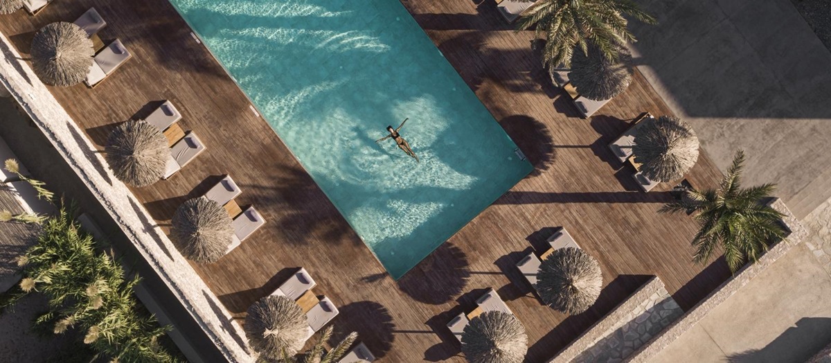Aerial view of guests swimming in pool surrounded by loungers and parasols at luxury hotel OKU Kos in Greece