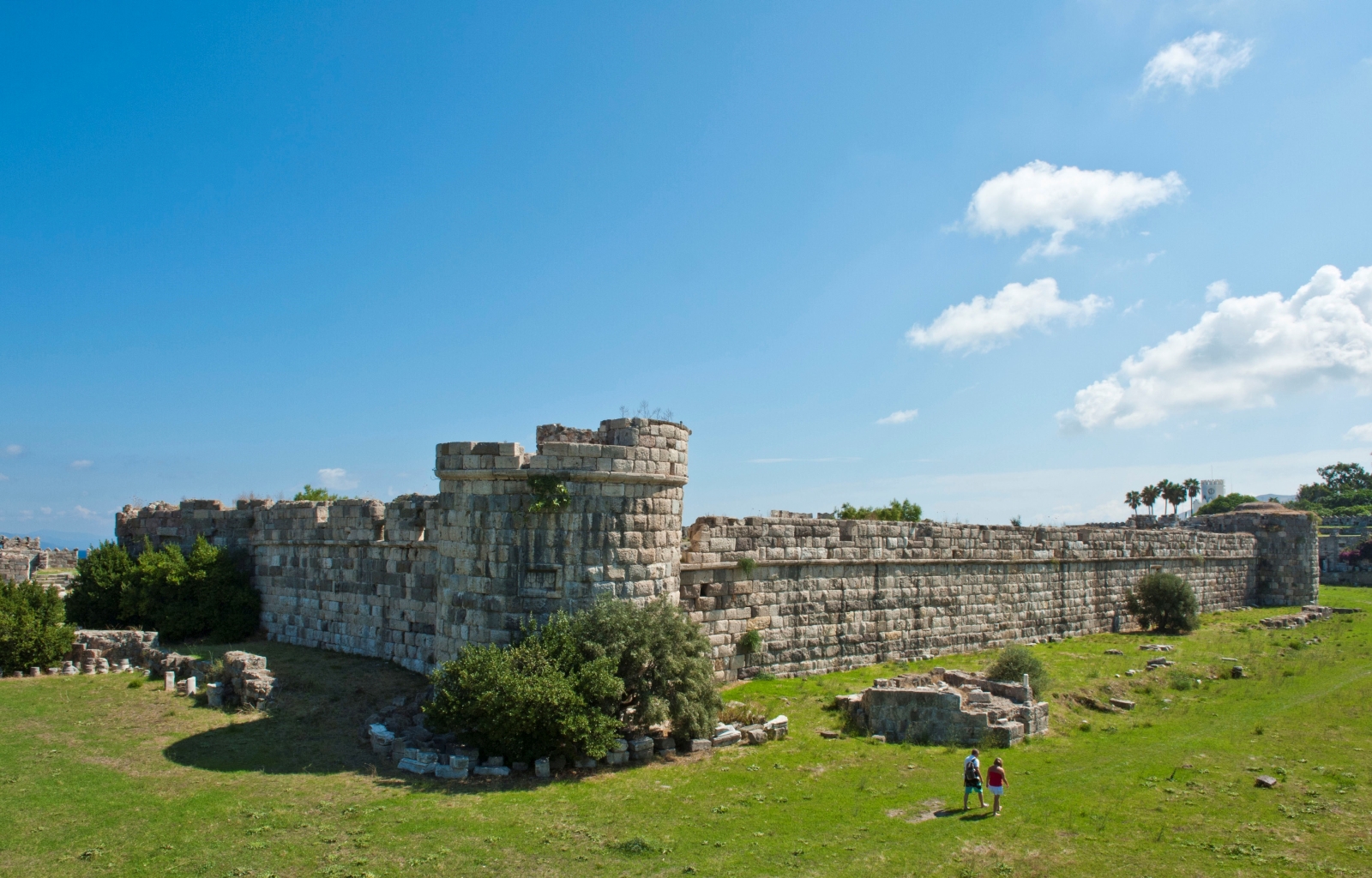 Castle ruins with two people walking past on grass