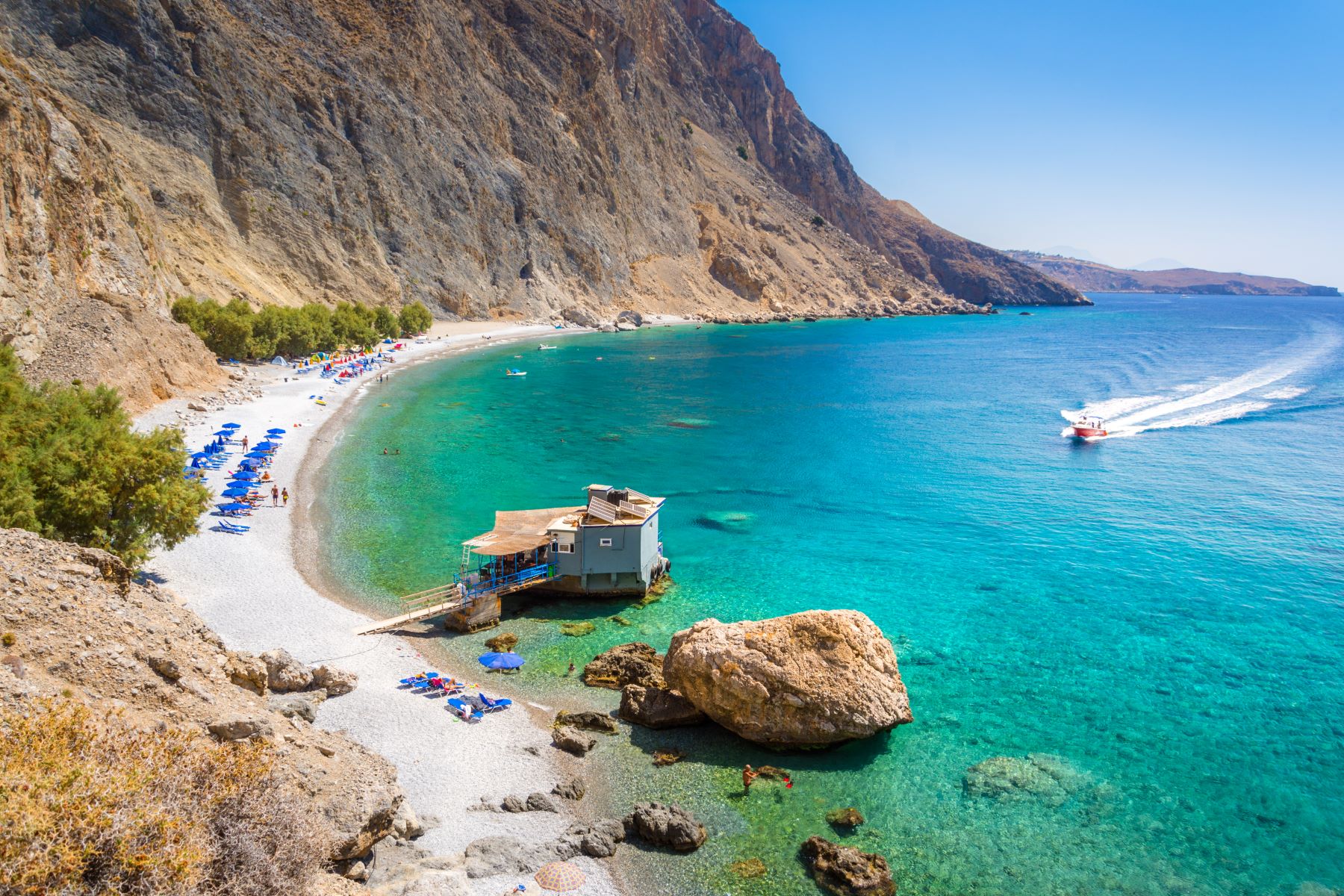 A boat sailing towards the jetty at Glyka Nera beach in Crete