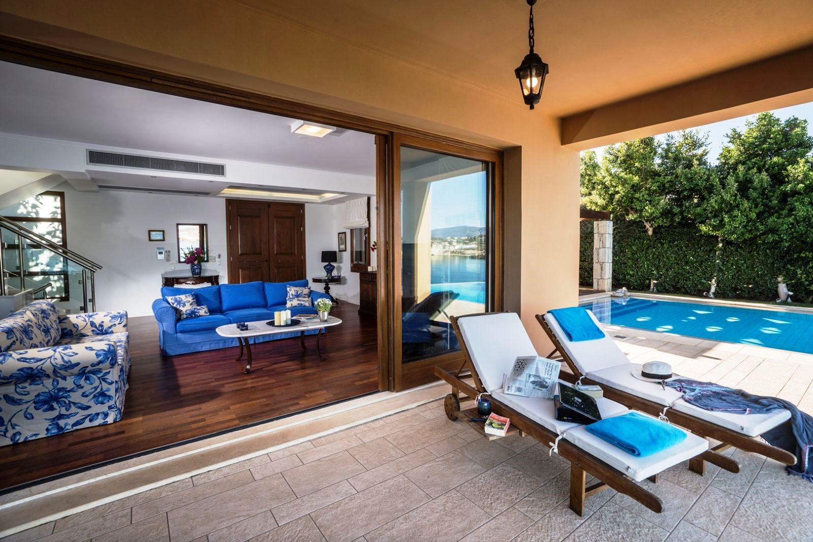 Undercover terrace with two sunbeds and big glass sliding doors leadig to sitting room at villa anemos in crete