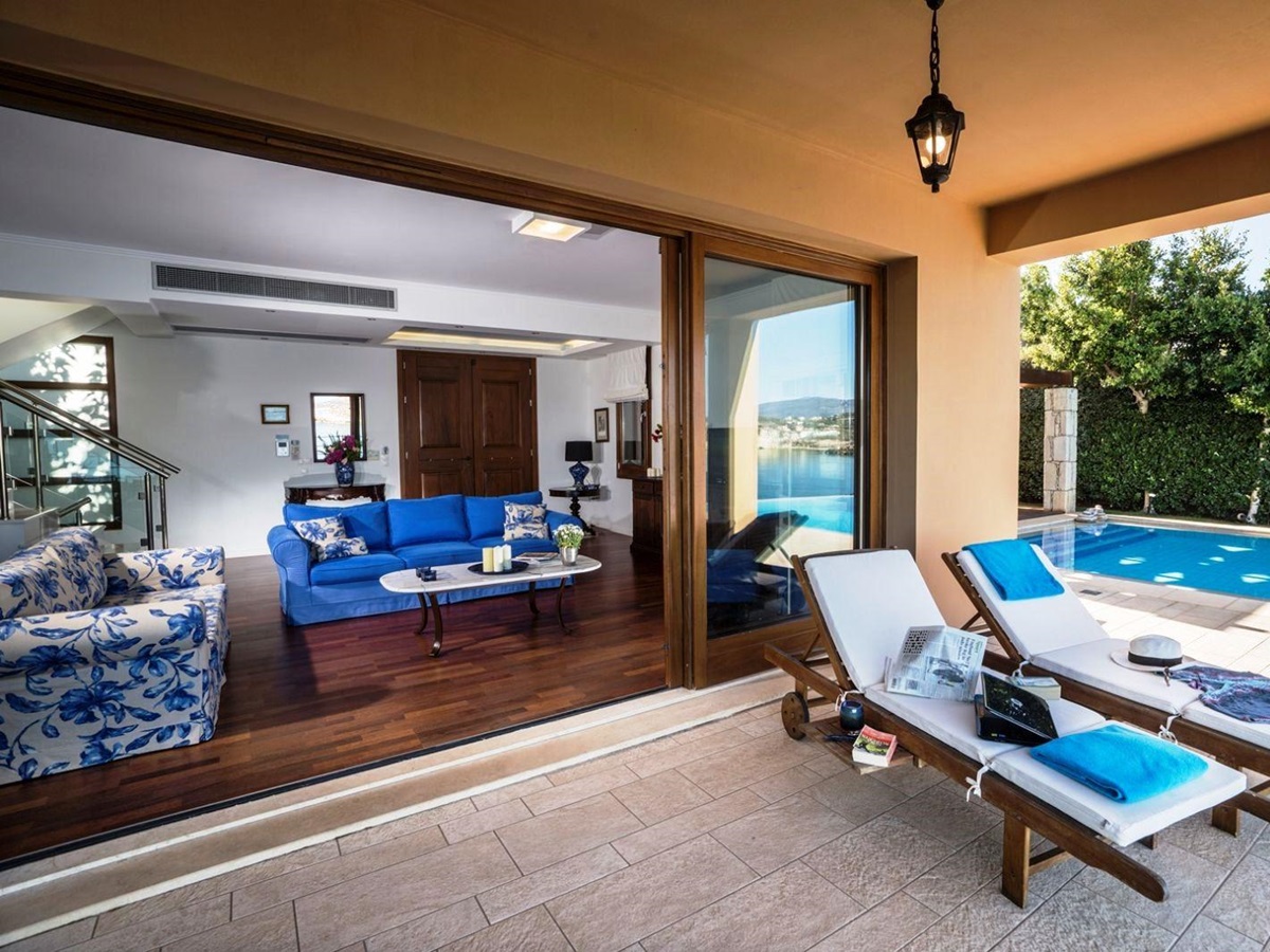 Undercover terrace with two sunbeds and big glass sliding doors leadig to sitting room at villa anemos in crete