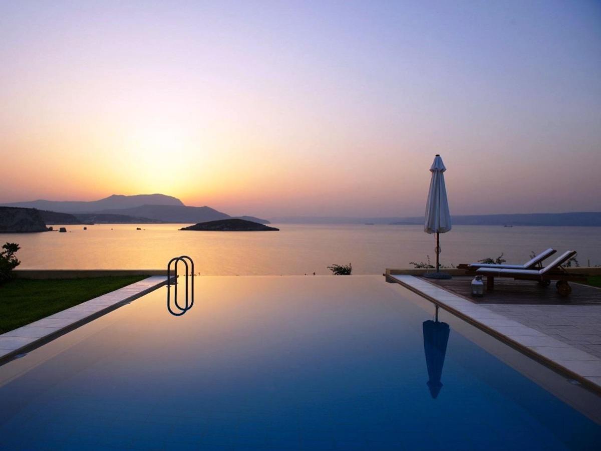 Swimming pool overlooking sea and mountains in the distance at sunset at villa anemos in crete