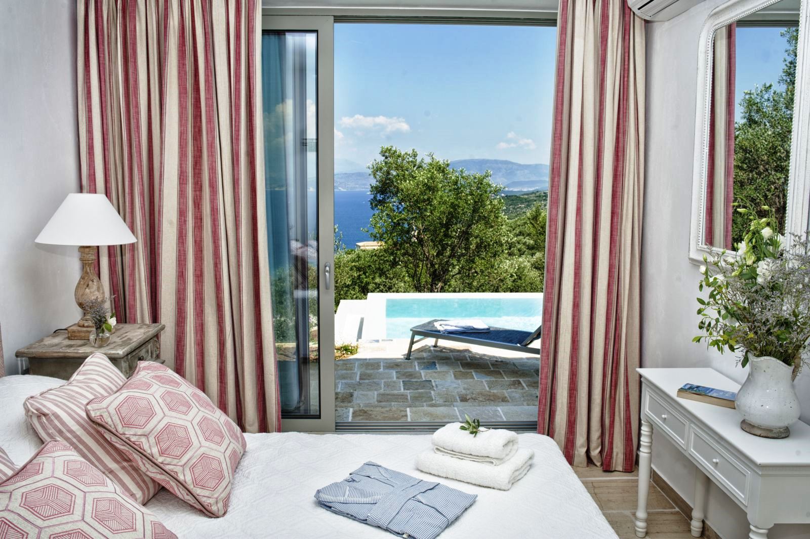 bedroom with pink striped curtains and sliding glass doors out to pool at villa apraos in corfu, Greece