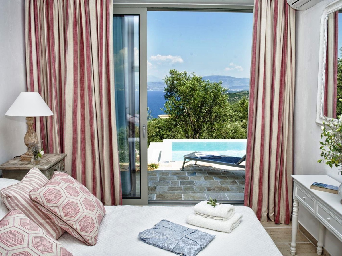 bedroom with pink striped curtains and sliding glass doors out to pool at villa apraos in corfu, Greece