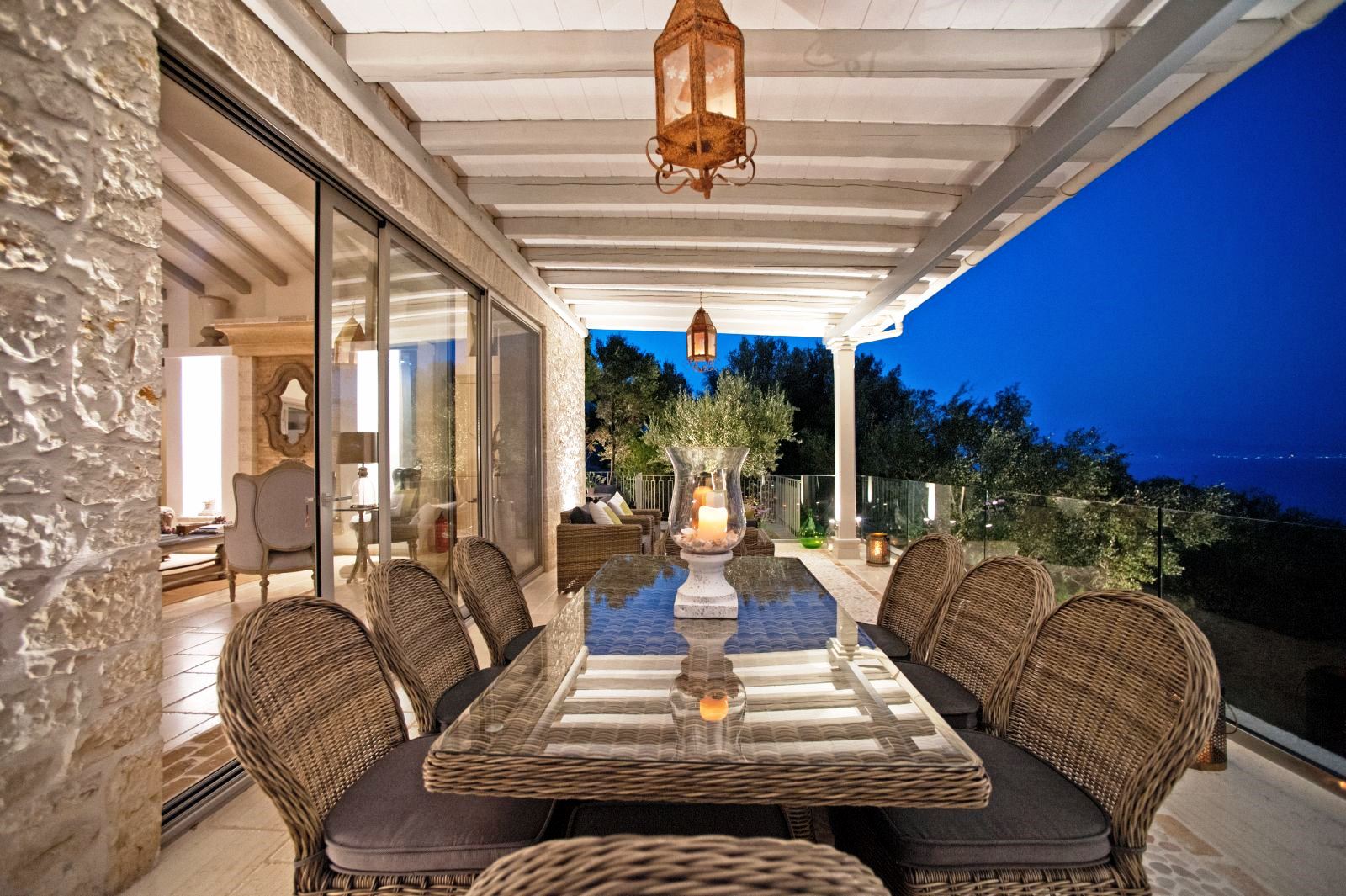 dining terrace at sunset with long wicker glass topped table and 8 chairs at villa apraos in corfu, Greece