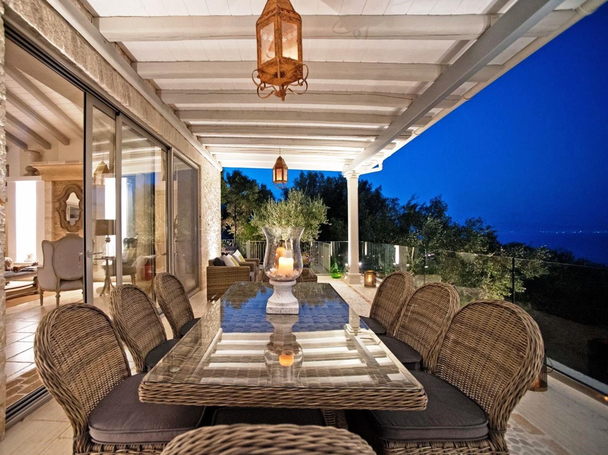 dining terrace at sunset with long wicker glass topped table and 8 chairs at villa apraos in corfu, Greece