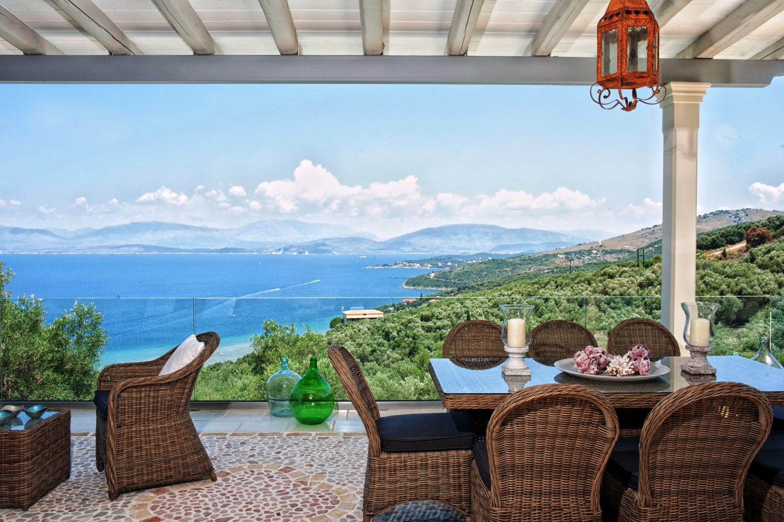 covered terrace with wicker table and chairs and views of the Ionian channel at villa apraos in corfu, Greece
