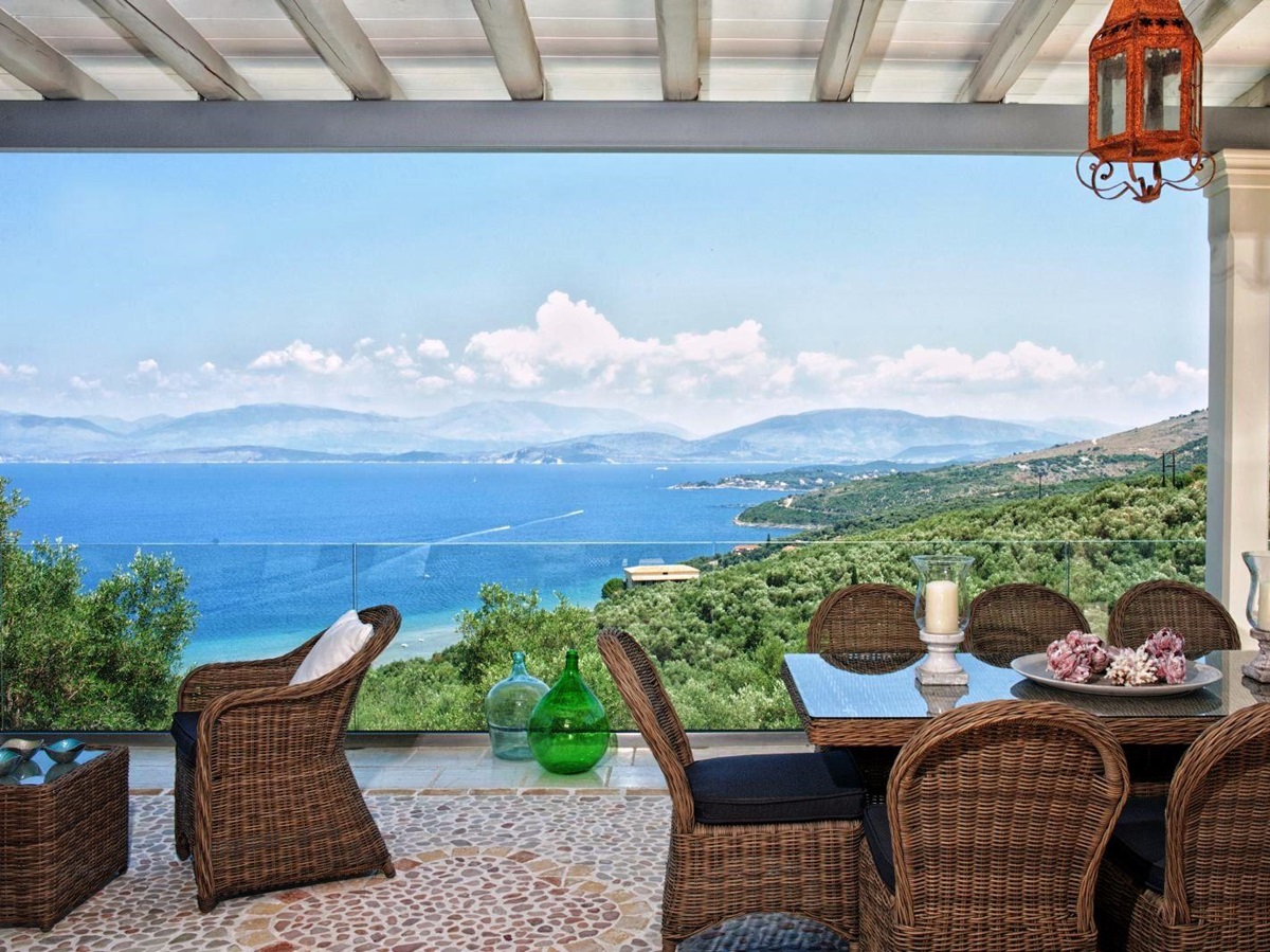 covered terrace with wicker table and chairs and views of the Ionian channel at villa apraos in corfu, Greece