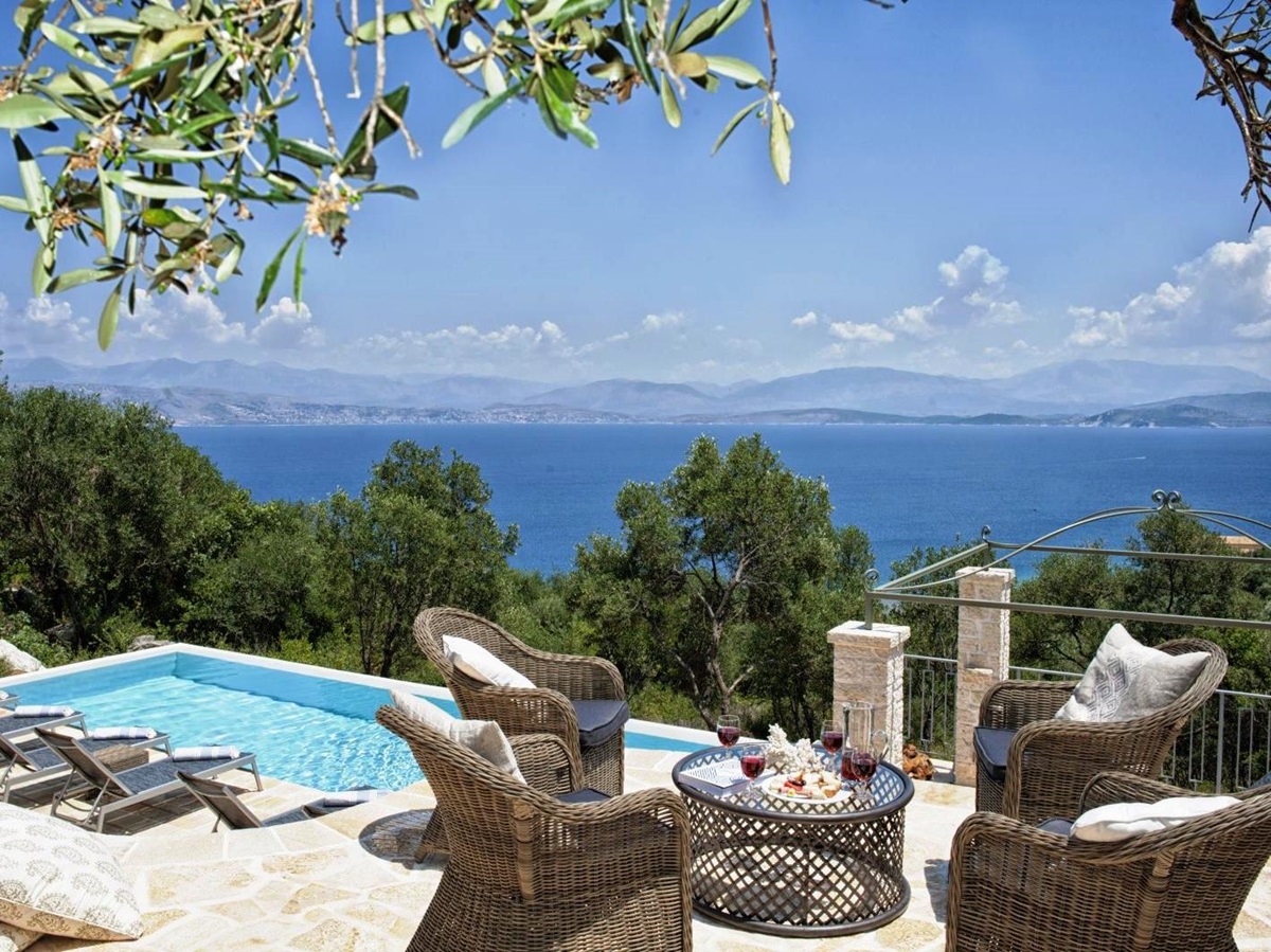 sun terrace with 4 wicker chairs and a table overlooking the pool with views of the sea at villa apraos in corfu, Greece