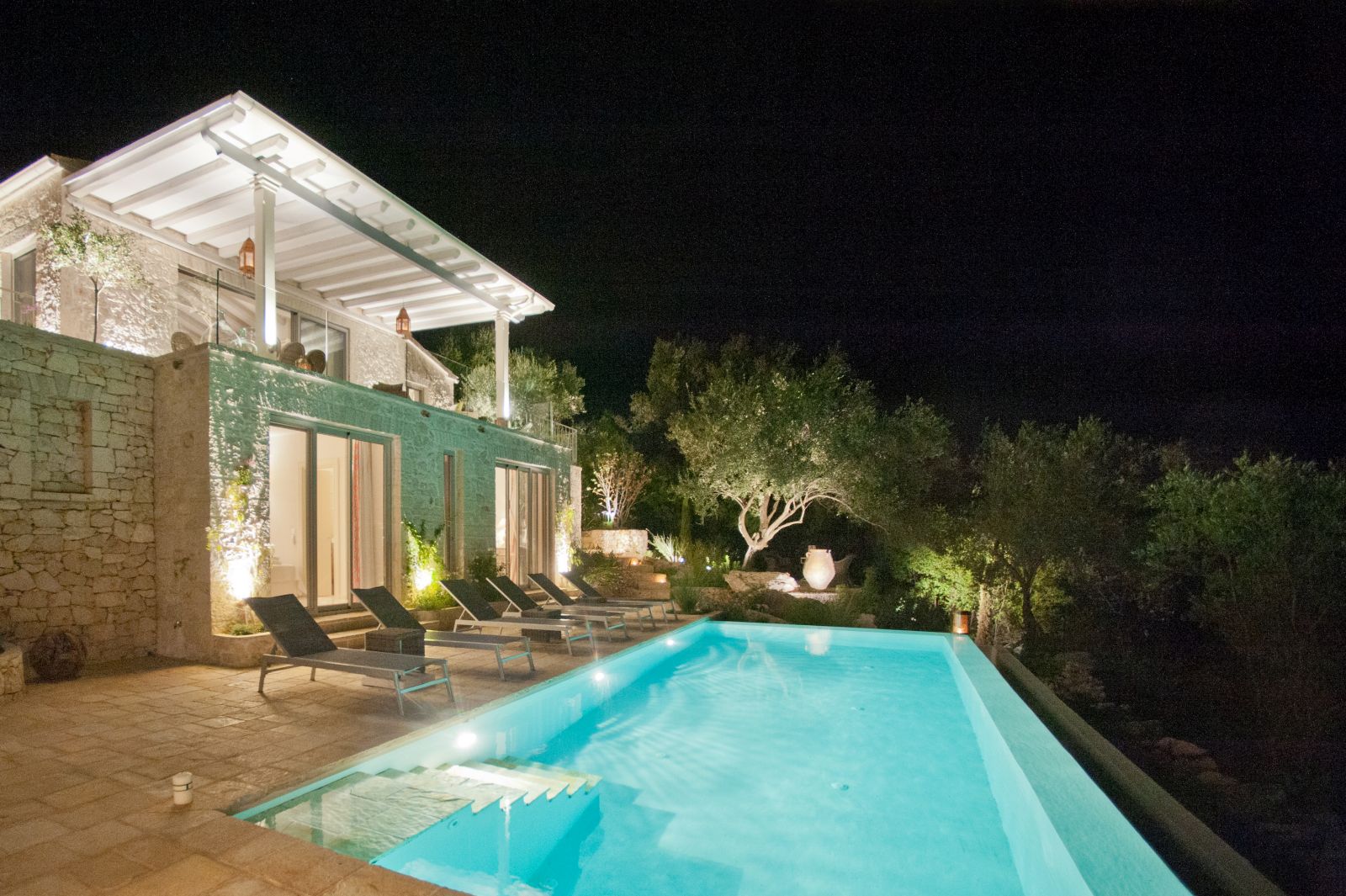 swimming pool lit up at night in front of at villa apraos in corfu, Greece