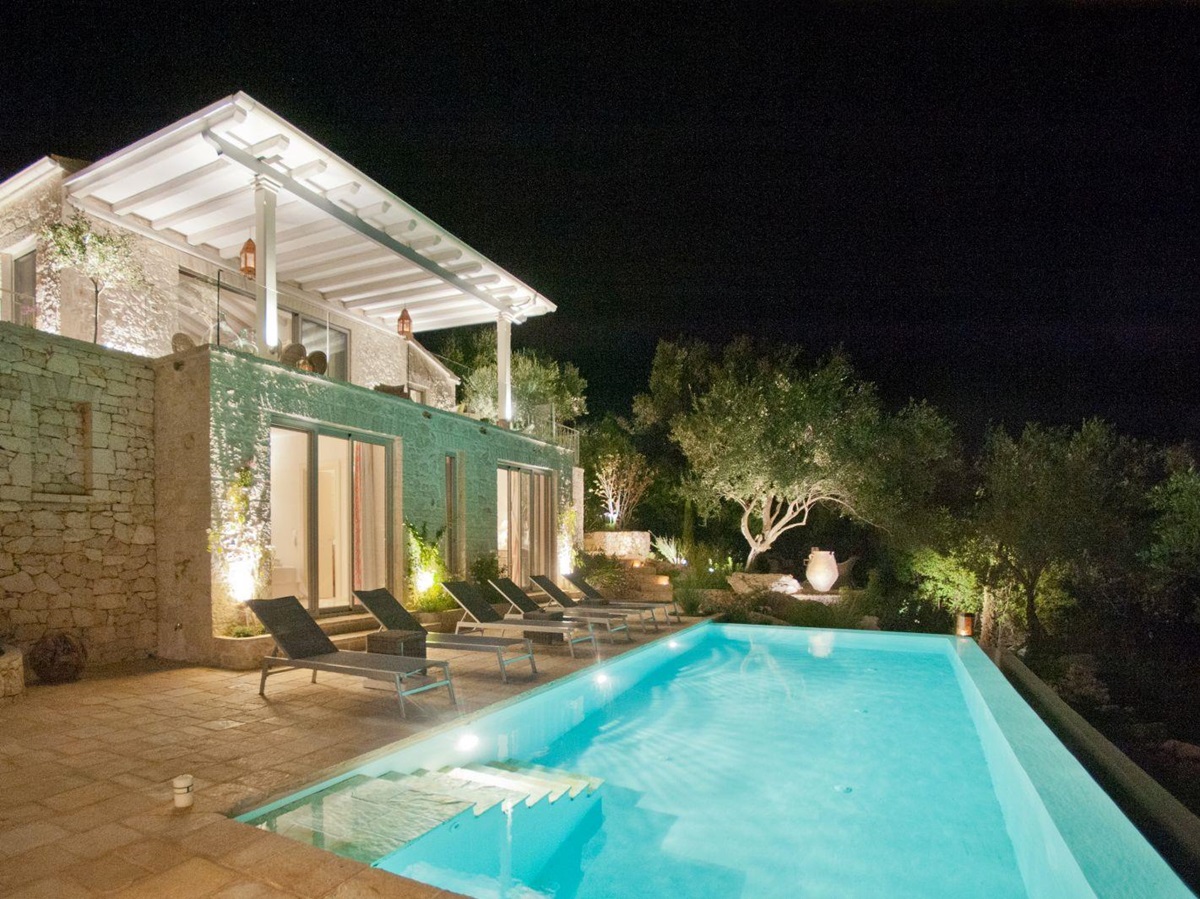 swimming pool lit up at night in front of at villa apraos in corfu, Greece