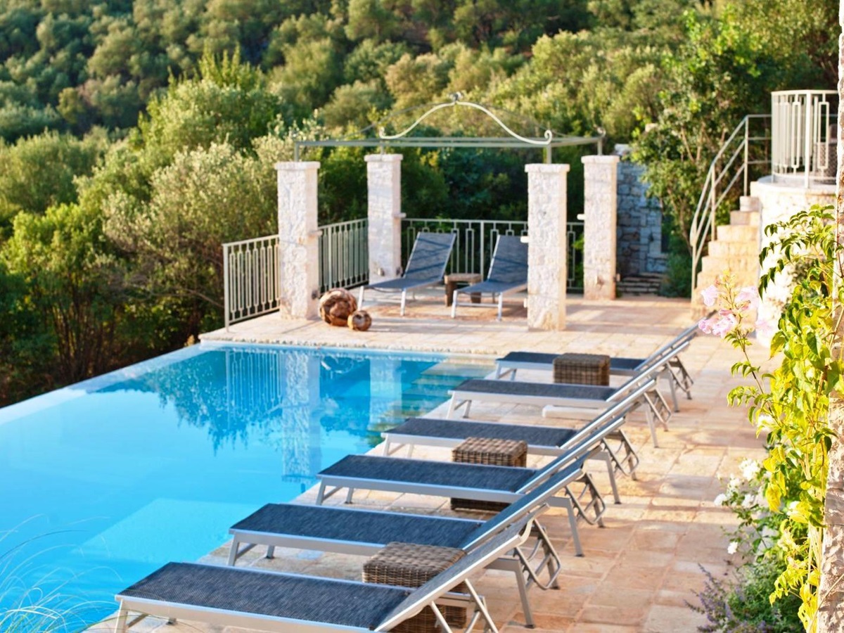6 blue sun beds overlooking the pool with trees in the background at villa apraos in corfu, Greece
