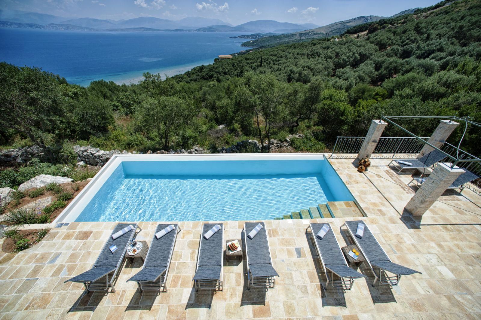 swimming pool and 6 blue sun beds overlooking the sea at villa apraos in corfu, Greece