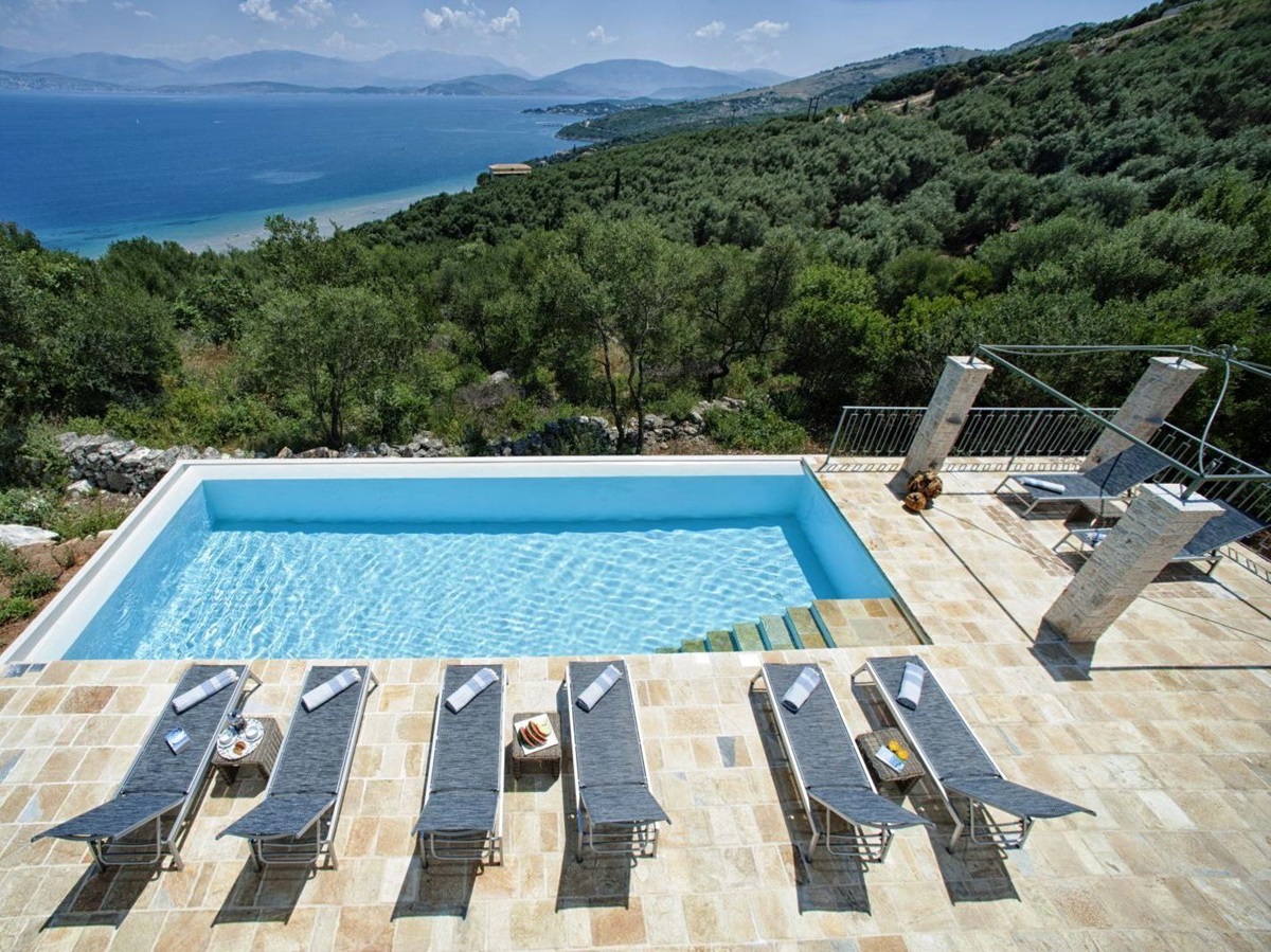 swimming pool and 6 blue sun beds overlooking the sea at villa apraos in corfu, Greece