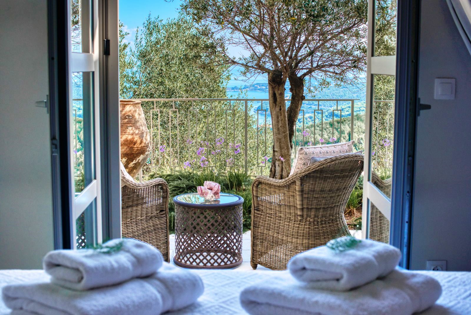 2 wicker chairs and round table on balcony overlooking the sea at villa apraos in corfu, Greece