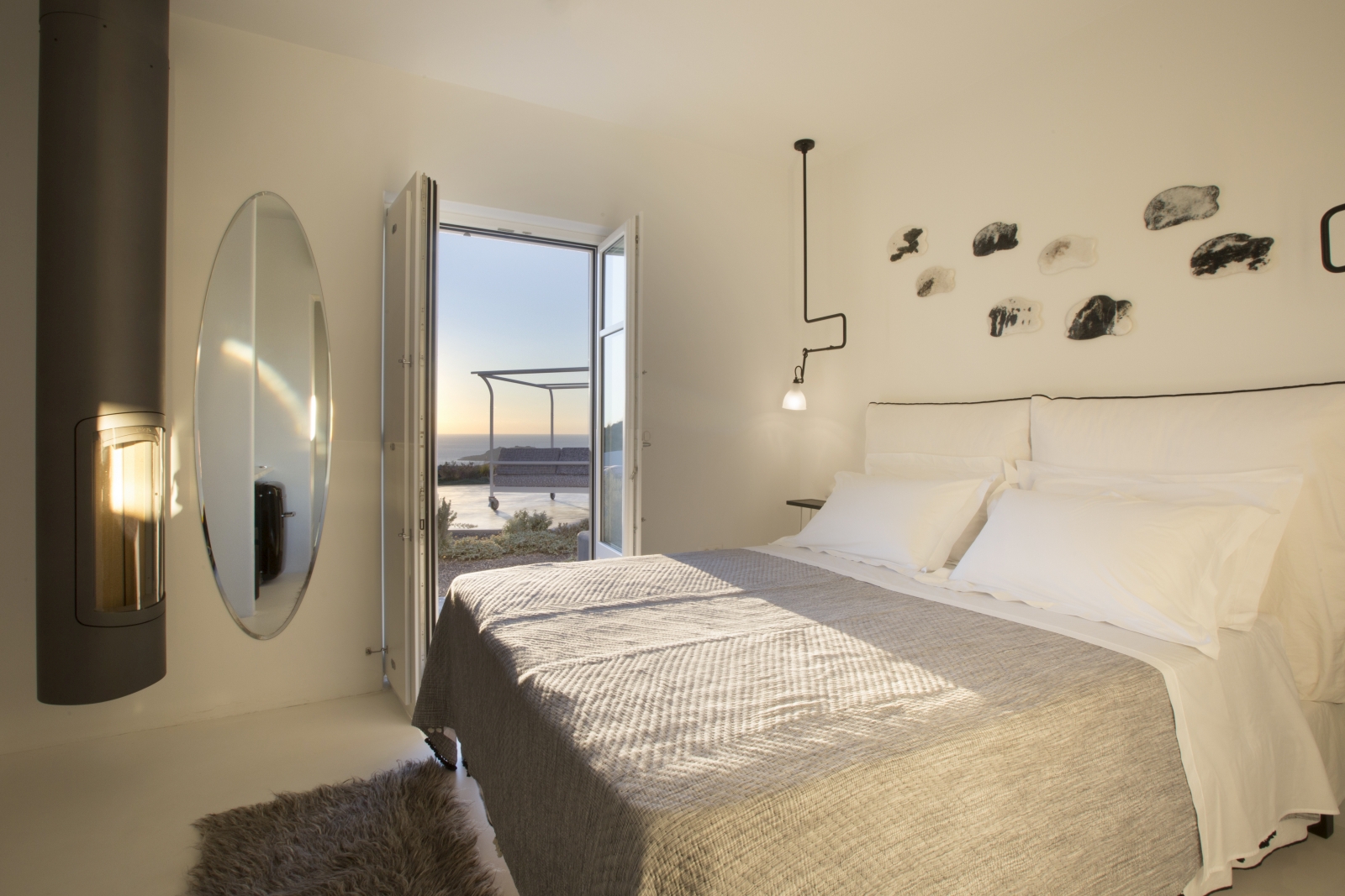 Bedroom with double bed, lamp, large mirror, heater and French doors to terrace at Erosantorini on Santorini, Greece