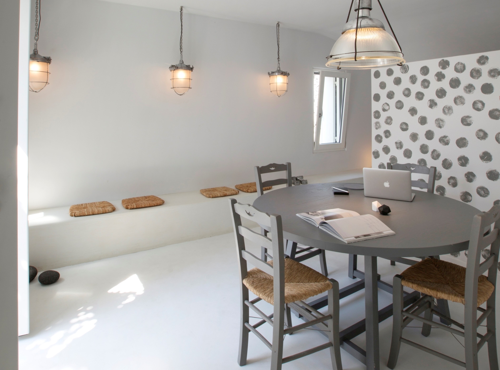 Dining area with round table, chairs, light, benches and lamps at Erosantorini on Santorini, Greece