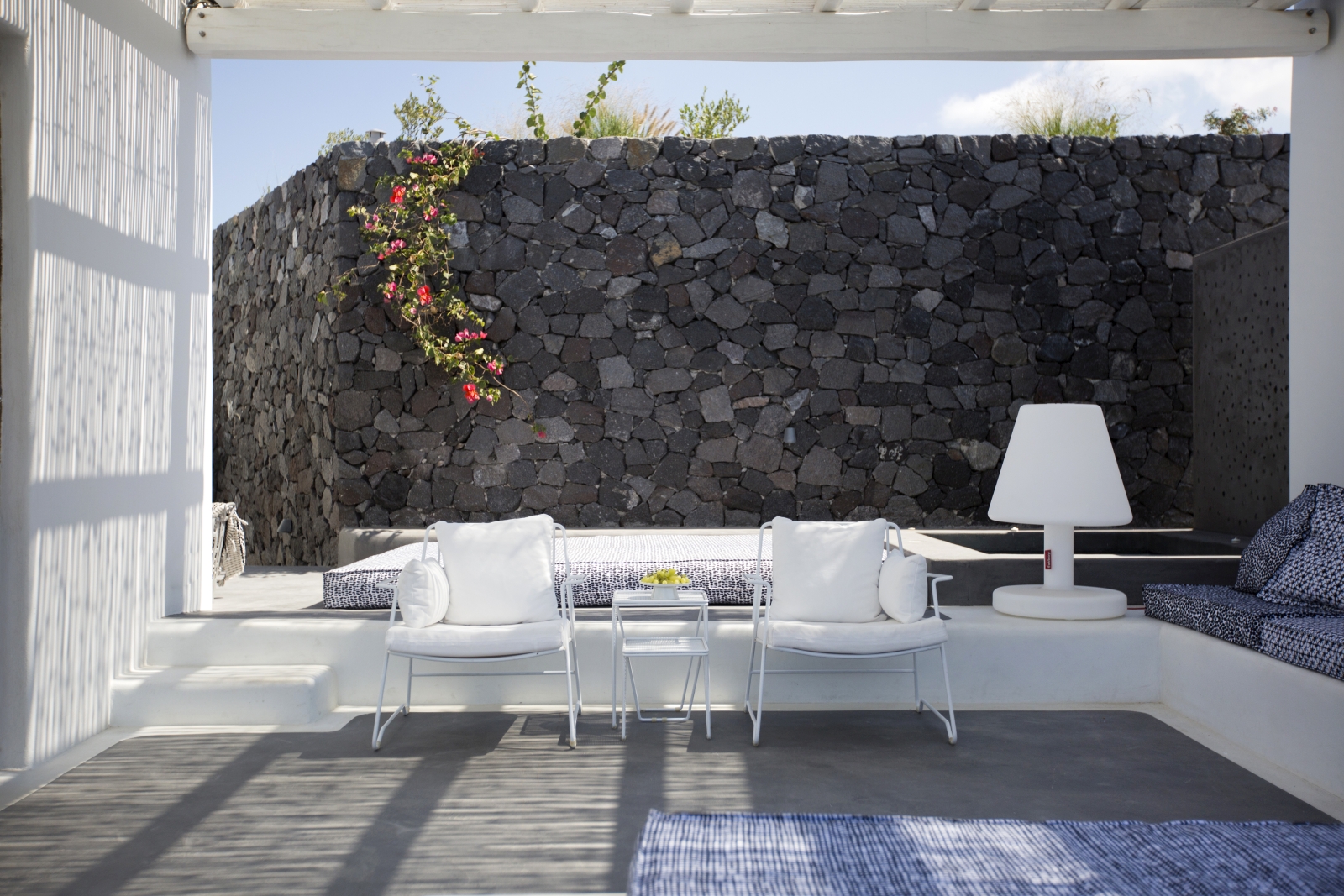 Outdoor lounge area with comfy benches and chairs, lamp and jacuzzi at Erosantorini on Santorini, Greece
