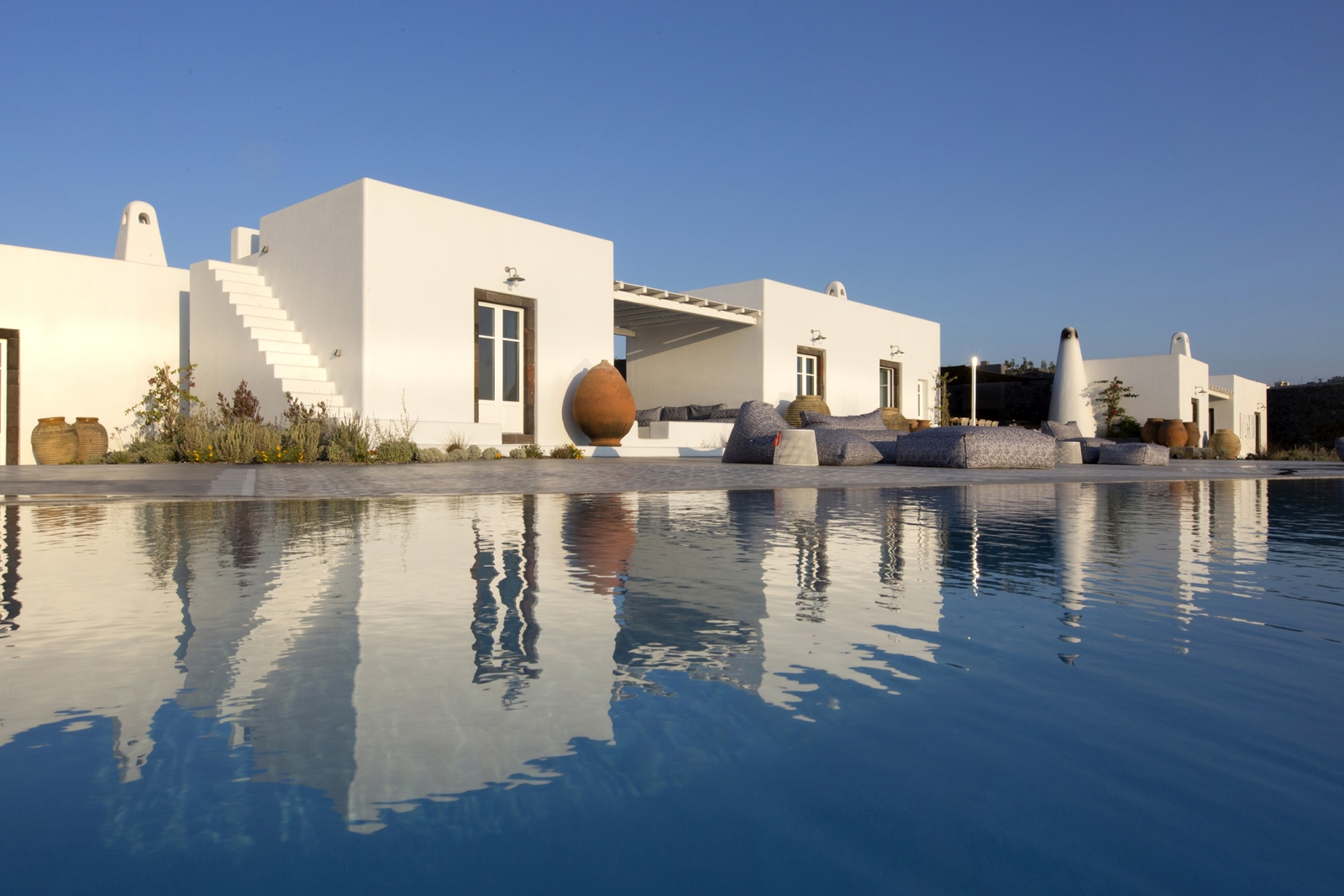 Pool, terrace with comfy chairs and villa at Erosantorini on Santorini, Greece