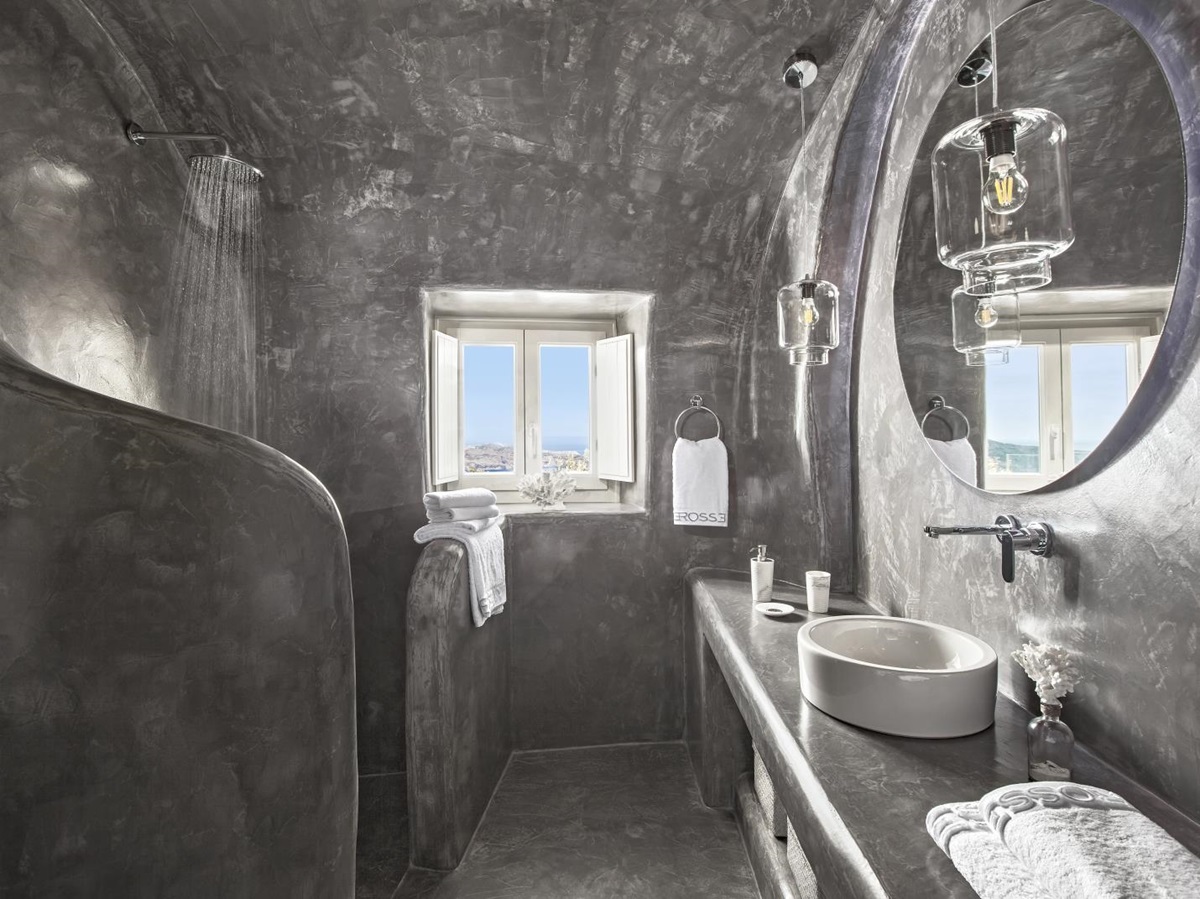 Bathroom with grey walls, sink, mirror, hanging lights, shower and window at Erossea on Santorini, Greece