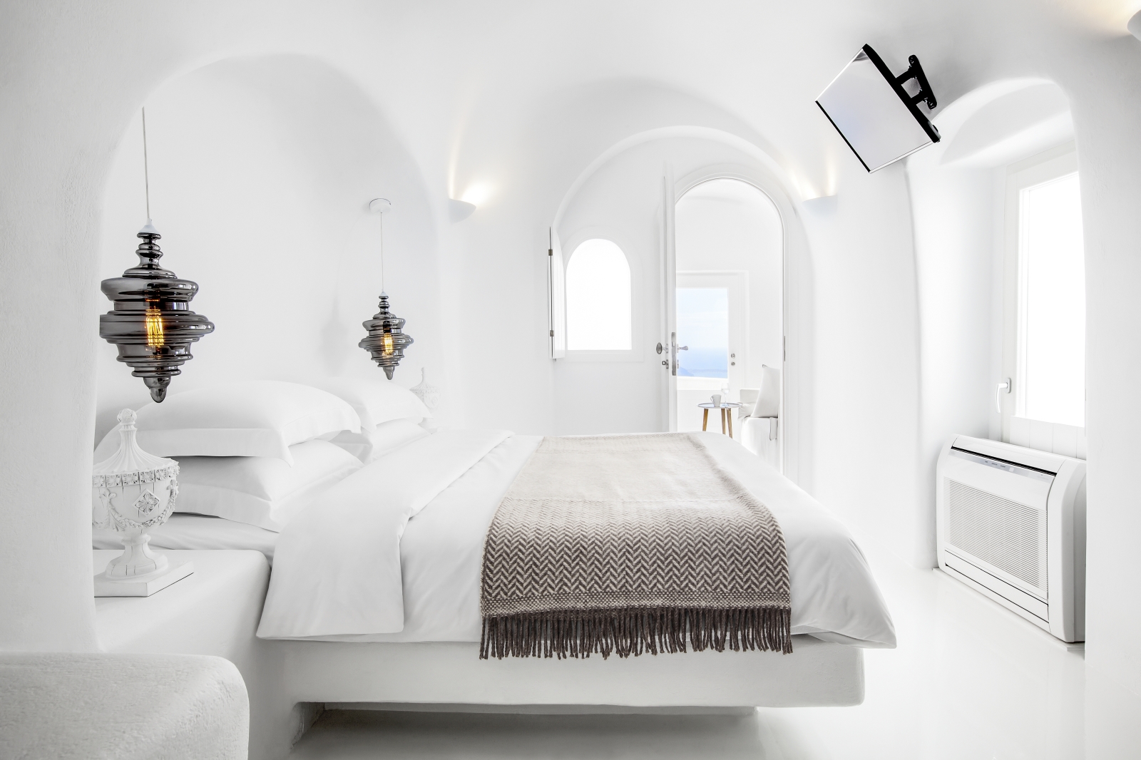 Bedroom with double bed, lamps & hanging lights at Erossea on Santorini, Greece