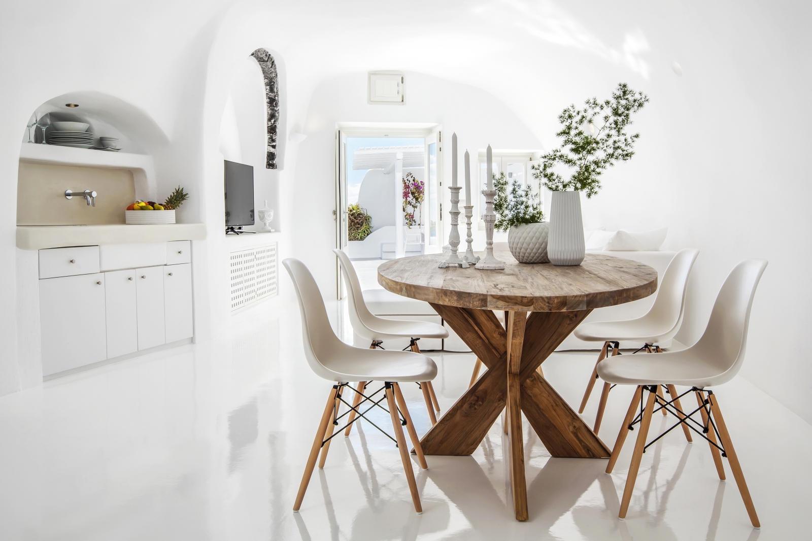 Kitchen with table, chairs, plants, candles and sink at Erossea on Santorini, Greece