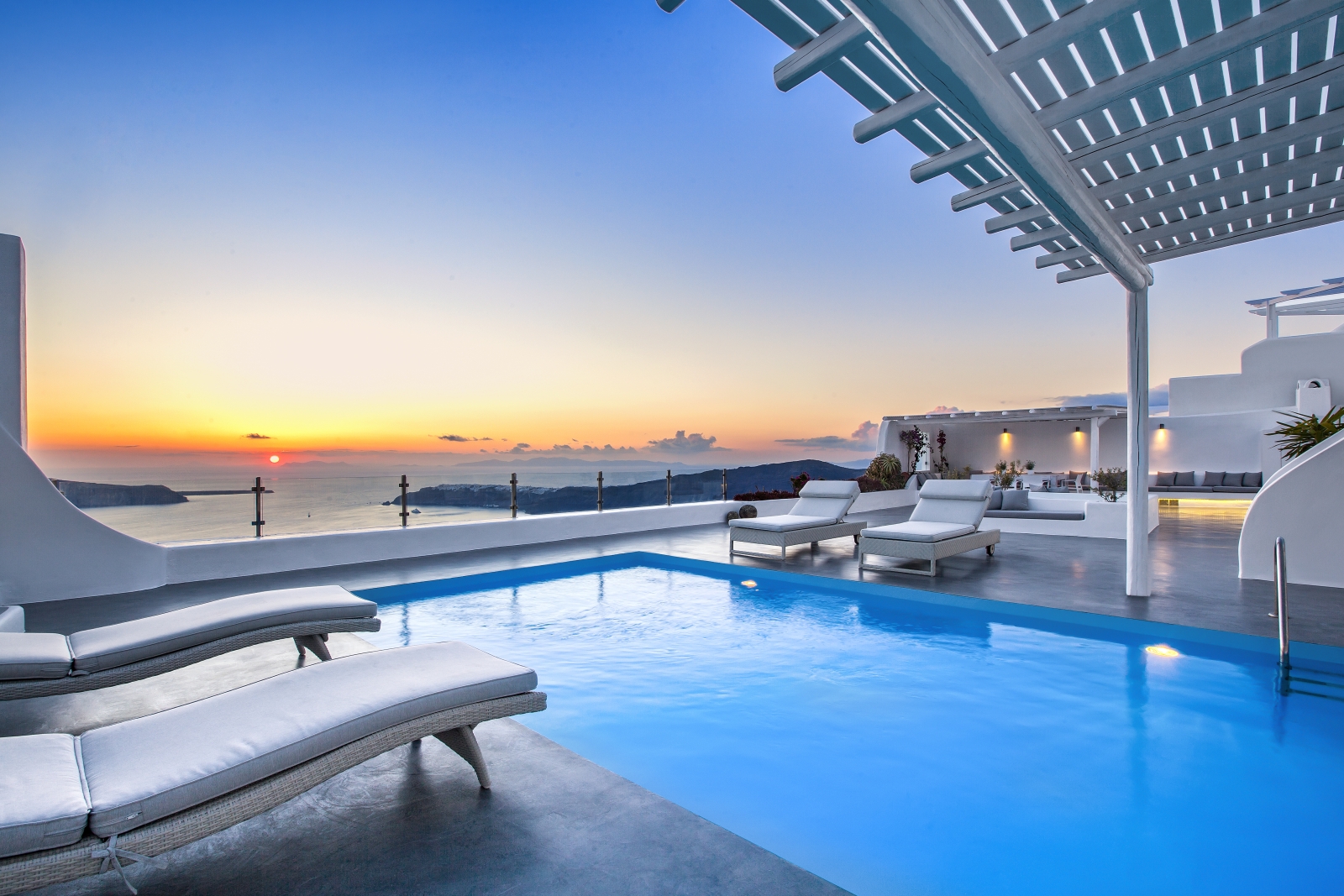 Pool and pool area with sun loungers and sunset sea view at Erossea on Santorini, Greece