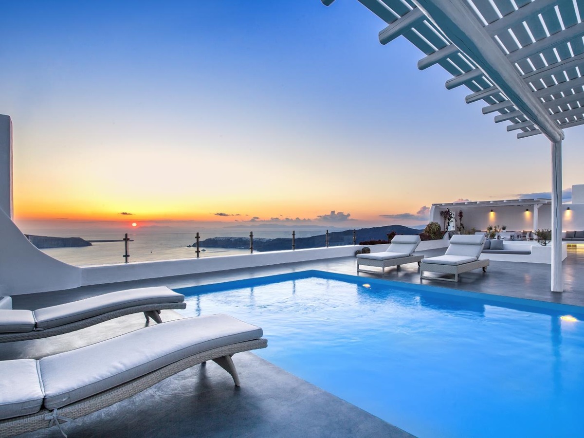 Pool and pool area with sun loungers and sunset sea view at Erossea on Santorini, Greece