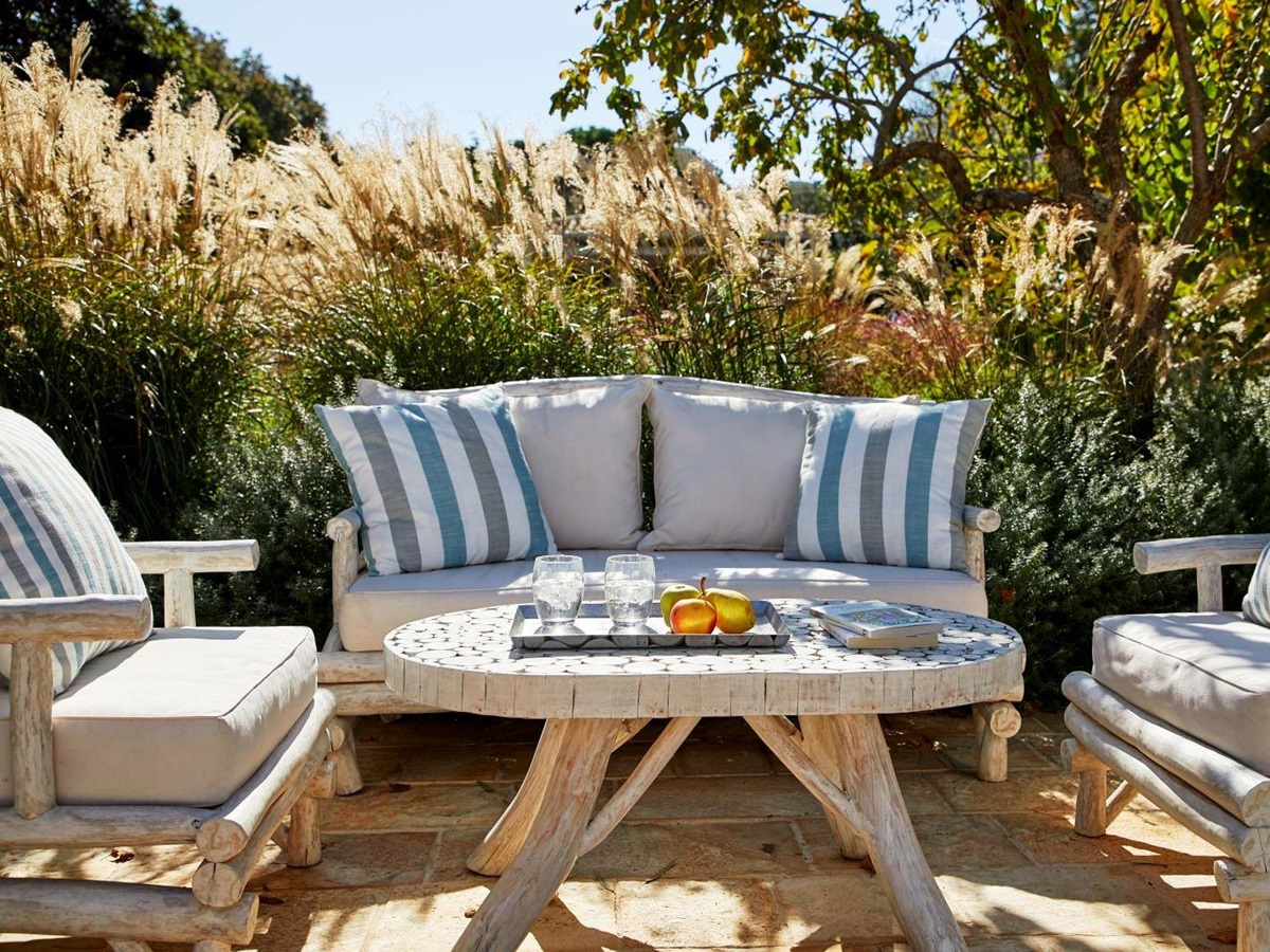 outdoor wooden table and chairs wth blue and white cushions on terrace at kogevina beach villa in corfu, greece