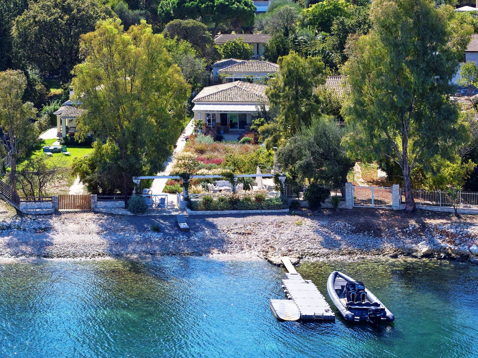 boat tied to jetty outside kogevina beach villa in corfu, greece