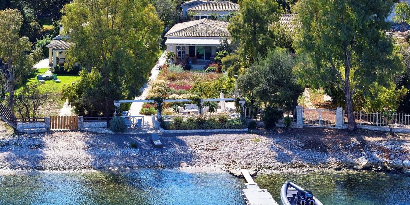 boat tied to jetty outside kogevina beach villa in corfu, greece