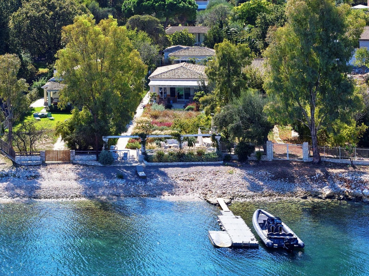 boat tied to jetty outside kogevina beach villa in corfu, greece