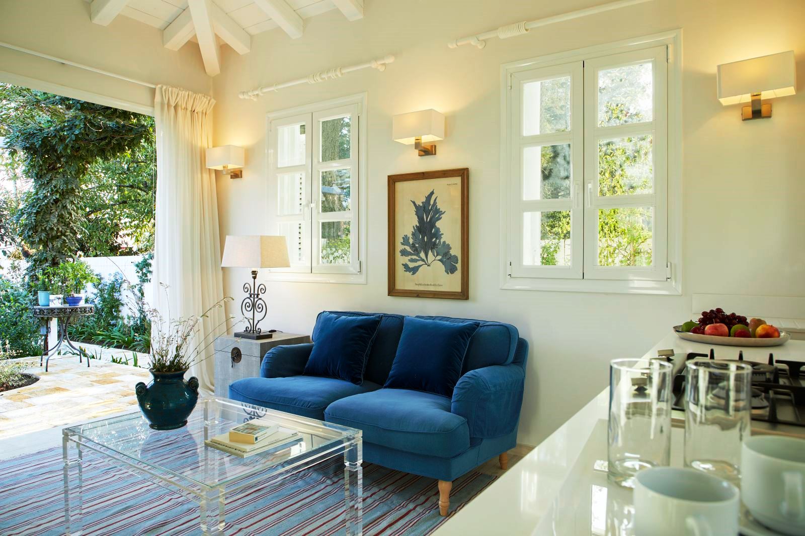 blue sofa and glass table in seating area at kogevina beach villa in corfu, greece