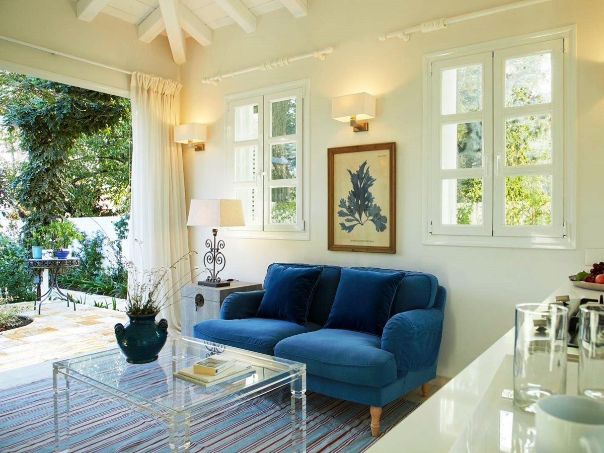 blue sofa and glass table in seating area at kogevina beach villa in corfu, greece