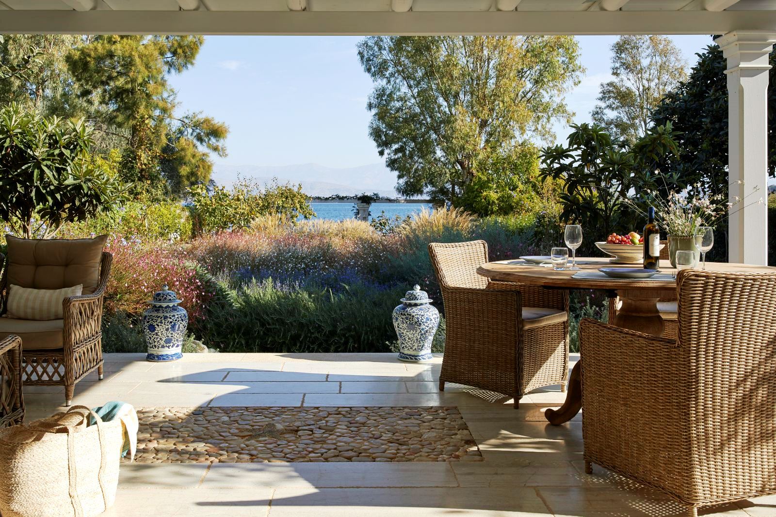 two wicker chairs and round table on the terrace at kogevina beach villa in corfu, greece