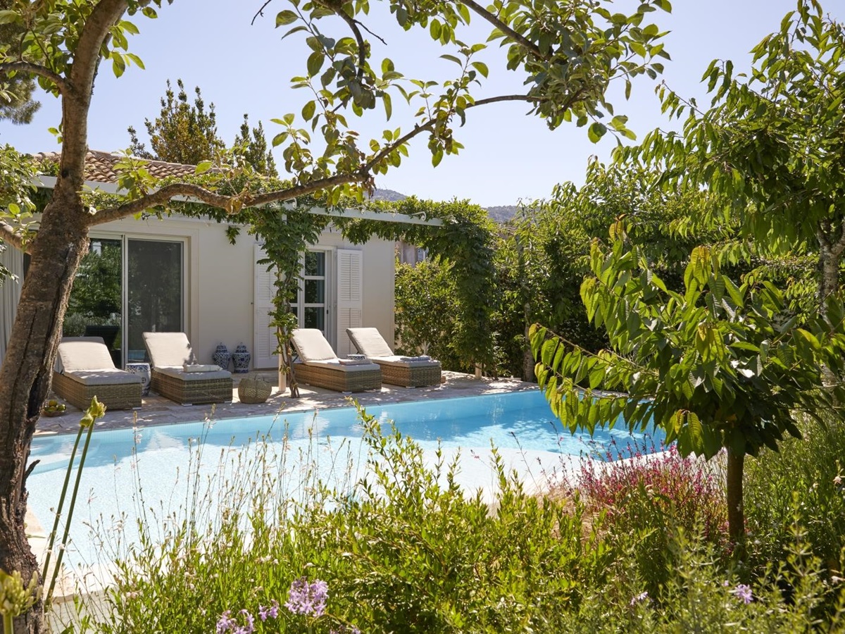 Pool and pool area with sun loungers, flowers and plants at Kogevina Beach Villa on Corfu, Greece
