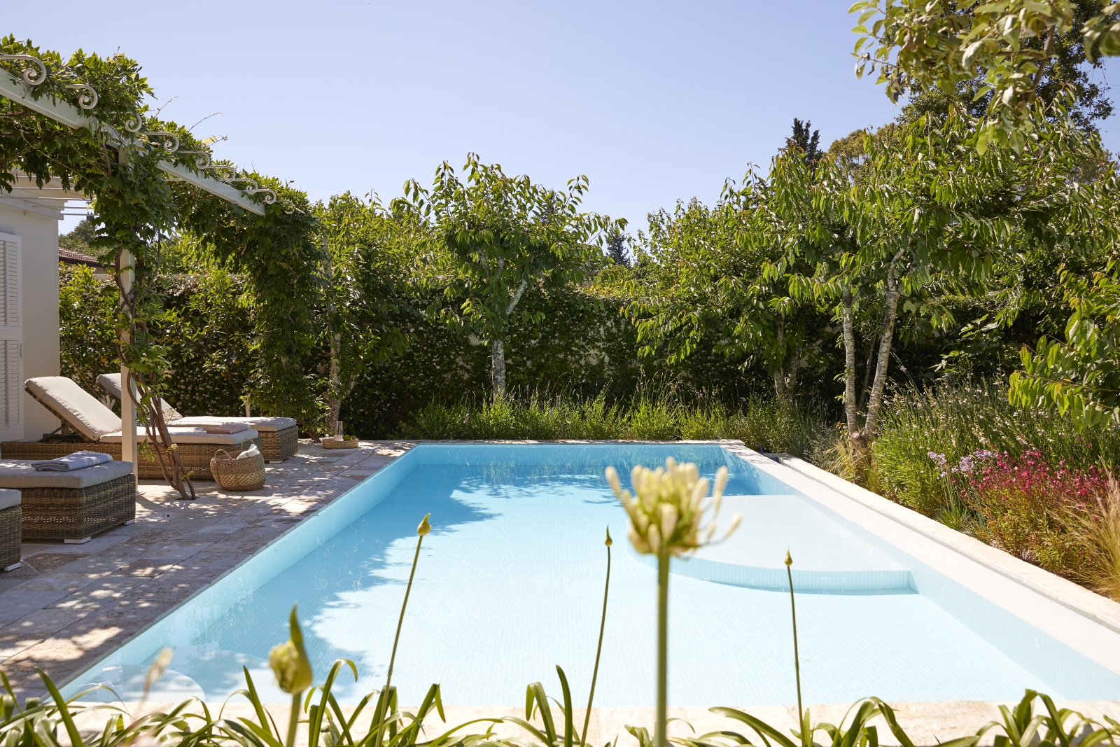 Pool and pool area with sun loungers and flowers at Kogevina Beach Villa on Corfu, Greece