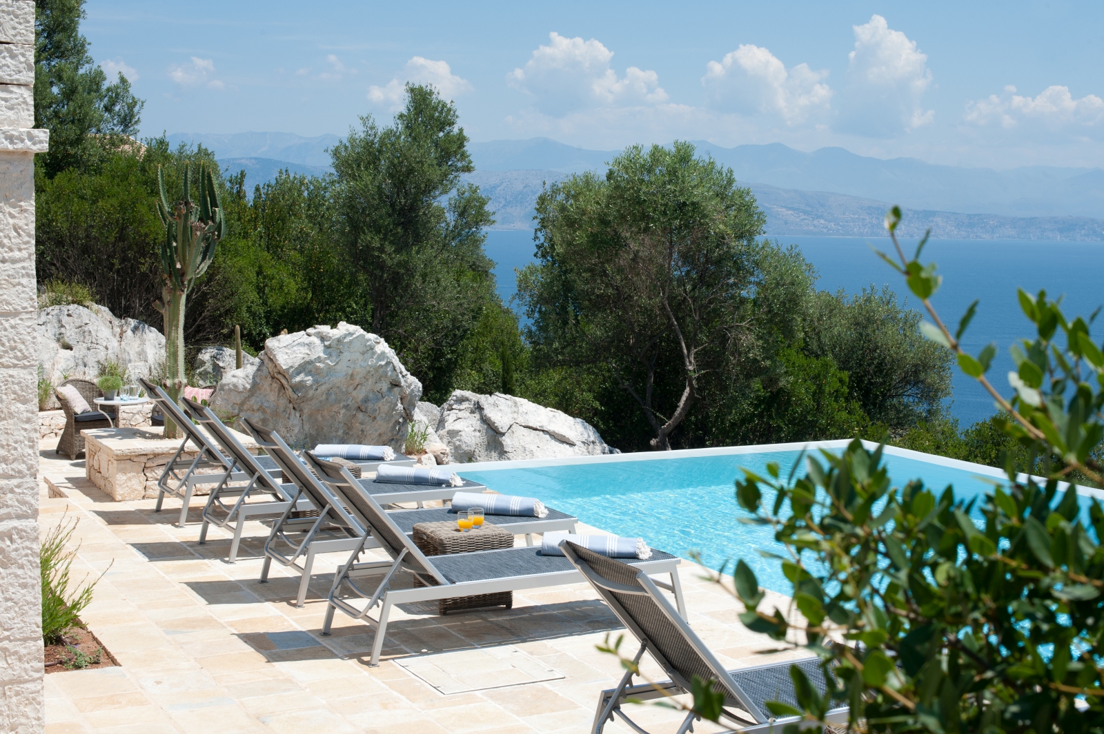Six pool loungers and lush greenery at Villa Dionysos, Corfu