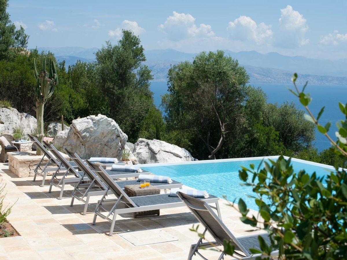 Six pool loungers and lush greenery at Villa Dionysos, Corfu