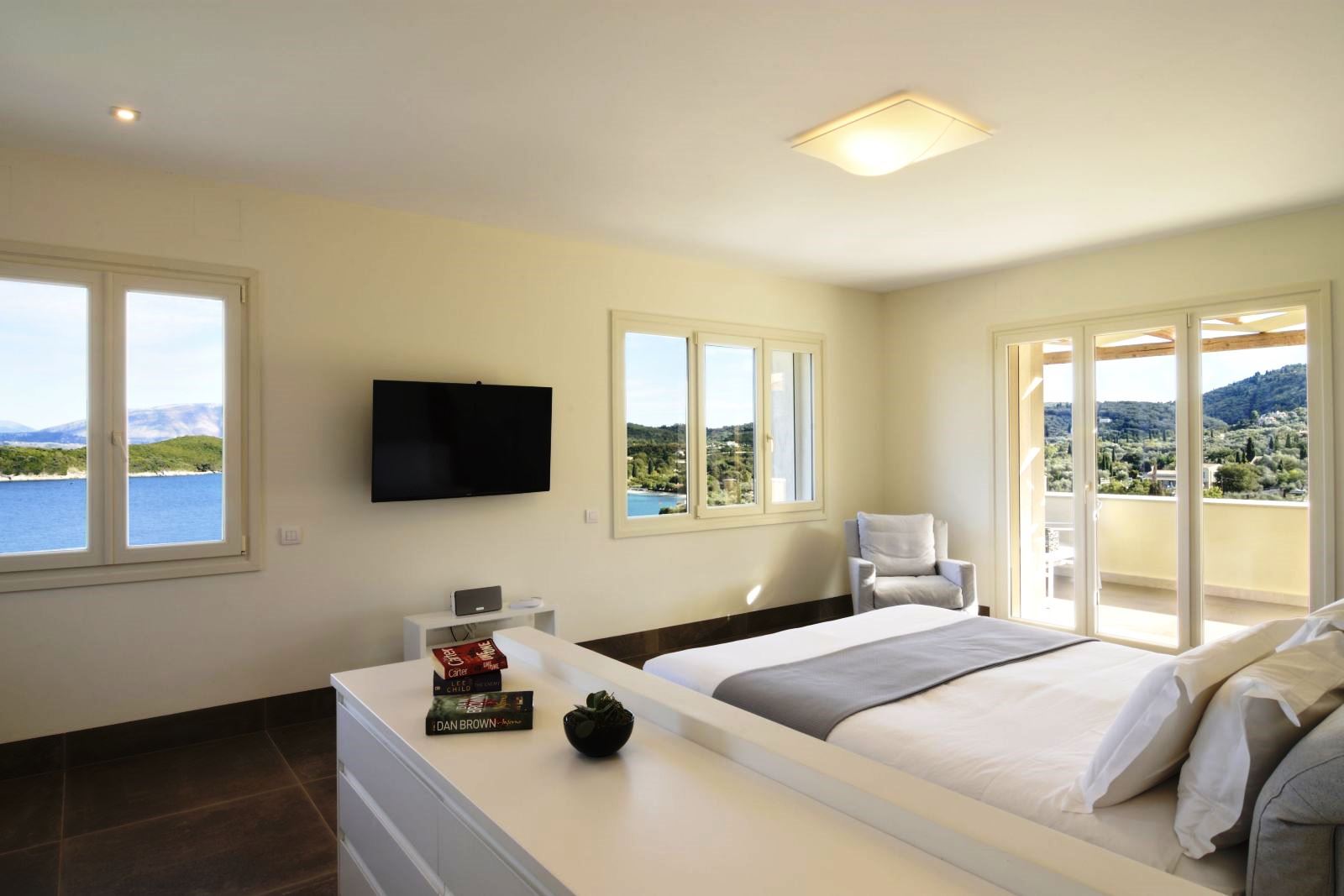 Double bedroom with white furniture and patio doors onto sun terrace at villa eleni in corfu, Greece